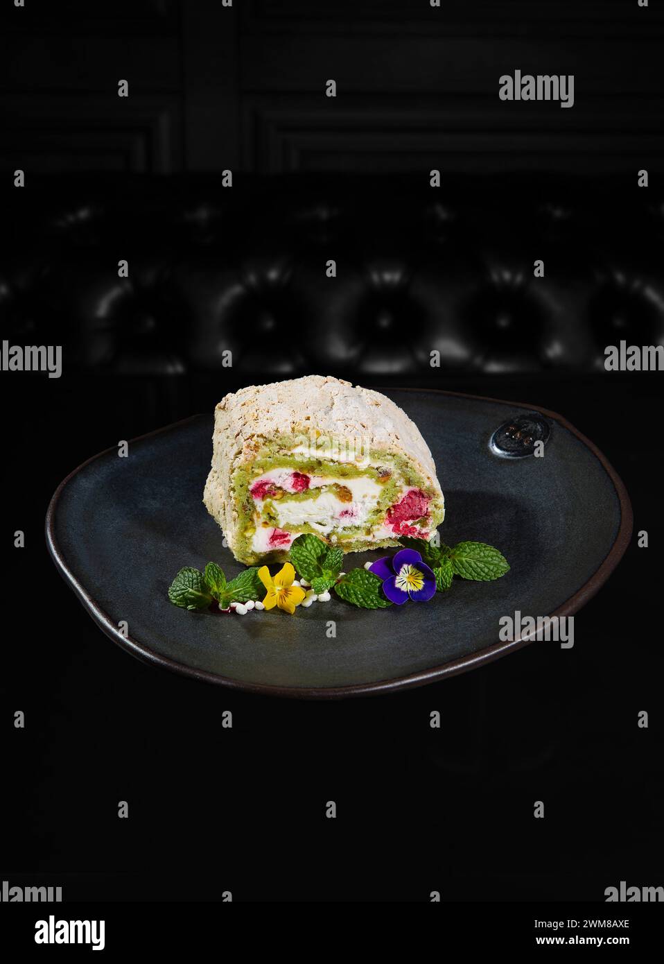 Rouleau de meringue aux framboises et pistaches décoratinf avec des fleurs et des feuilles de menthe dans le café de NYC Banque D'Images