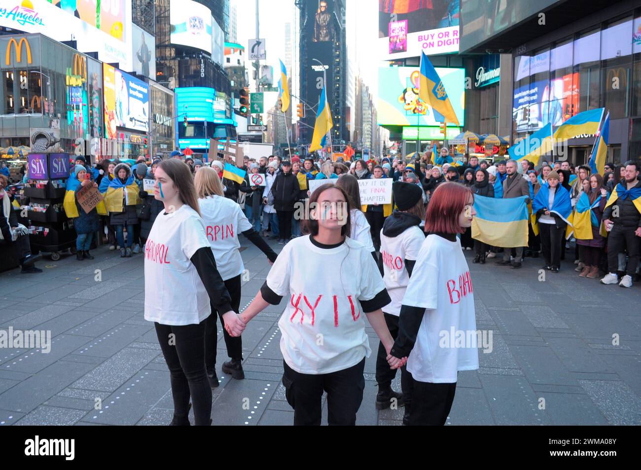 Des manifestants pro-Ukraine, portant chacun un t-shirt avec le nom d'une ville ukrainienne écrit dessus, se rassemblent à Times Square. Des manifestants se sont rassemblés à Manhattan, New York City, à l'occasion des deux ans de l'invasion russe de l'Ukraine. Les manifestants ont condamné l'invasion et se sont opposés au président russe Vladimir Poutine. Le week-end dernier, les forces russes ont capturé la ville ukrainienne orientale d'Avdiivka située sur la ligne de front. La perte de la ville survient alors qu'un paquet d'aide de 60 milliards de dollars pour l'Ukraine de la part des États-Unis a été bloqué à la suite de désaccords au Congrès. Président ukrainien, Volodymyr Zelen Banque D'Images