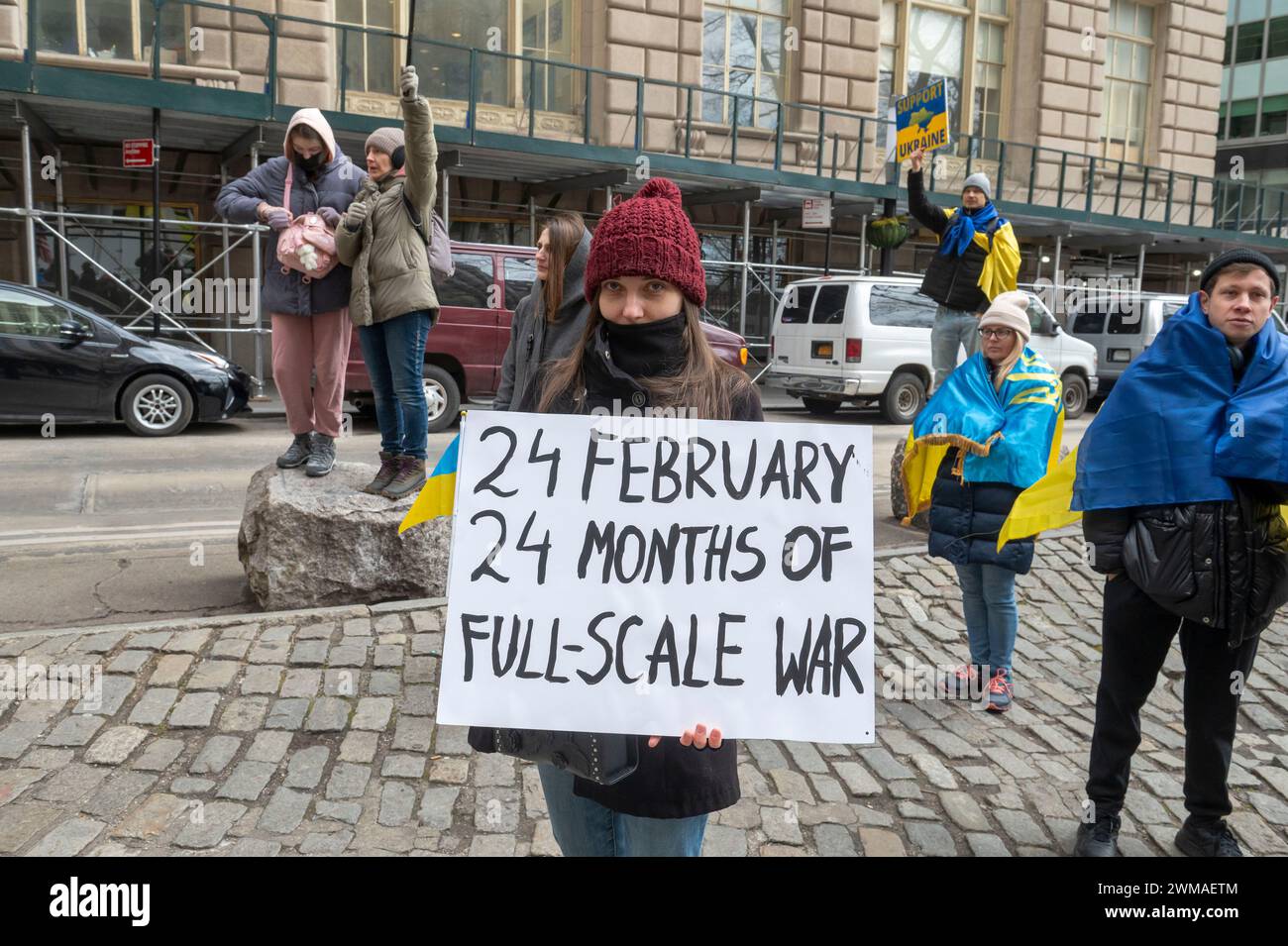 Une femme tient une pancarte « 24 FÉVRIER 24 MOIS DE GUERRE À GRANDE ÉCHELLE » lors d'une cérémonie de levée du drapeau pour l'Ukraine à l'occasion du deuxième anniversaire de l'invasion russe de l'Ukraine dans l'historique Bowling Green Park à Lower Manhattan. Entrant dans sa troisième année, la guerre inlassable de la Russie contre l'Ukraine a soulevé des inquiétudes quant à la durée pendant laquelle les pays occidentaux continueront à fournir des armes et d'autres formes de soutien à Kiev. La fourniture de munitions, d’armes et de main-d’œuvre est aujourd’hui un facteur critique dans un conflit qui a fait plus d’un demi-million de victimes et provoqué des déplacements massifs de civils. Banque D'Images