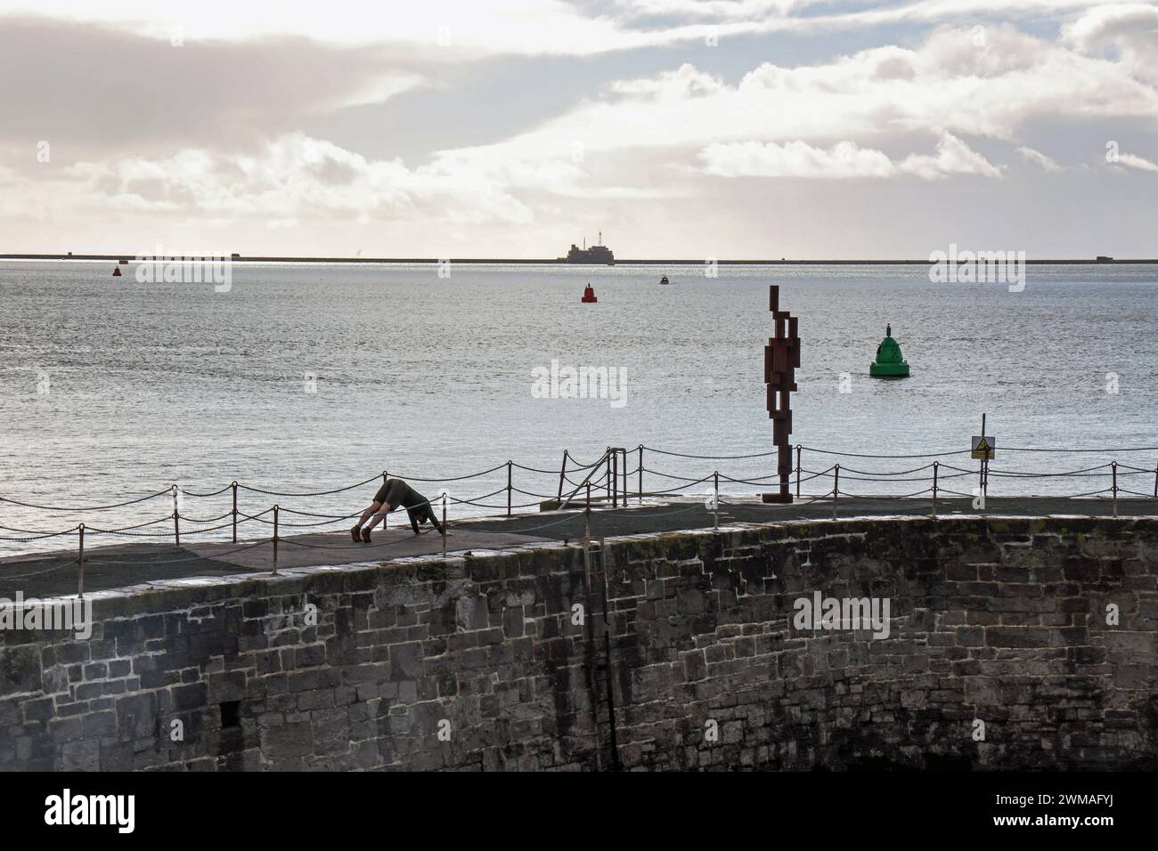 Pressez des exécutions ou vénérez les beaux-arts, un jeune homme avec la sculpture de 12 pieds «look II» de Sir Anthony Gormley sur West Hoe Pier Plymouth. Le controversé Banque D'Images