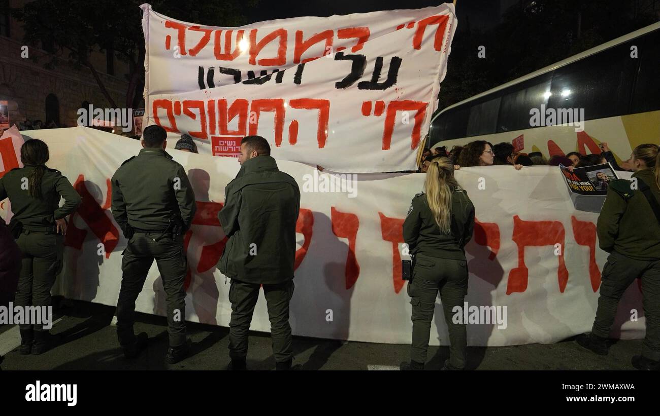 Des membres des forces de sécurité israéliennes bloquent la voie aux manifestants tenant des banderoles lors d'une manifestation près de la résidence officielle du premier ministre exigeant la libération des otages détenus par le Hamas dans la bande de Gaza le 19 février 2024 à Jérusalem. Israël Banque D'Images