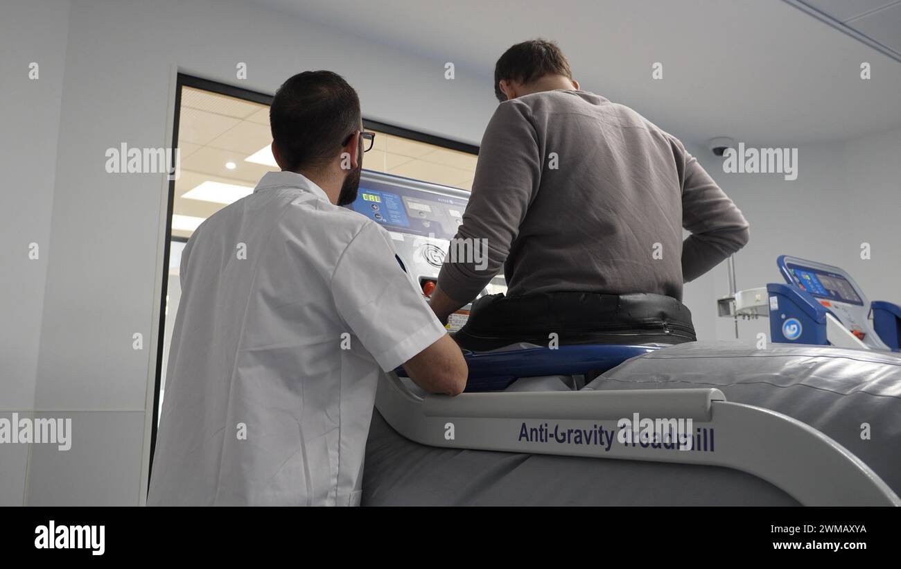 Un physiothérapeute aide un soldat israélien blessé à la jambe lors de combats à Gaza à marcher sur un appareil anti-gravité pendant une séance de physiothérapie au nouveau centre de réadaptation de Gandel de l’hôpital Hadassah – Mount. Scopus le 21 février 2024 à Jérusalem. Israël Banque D'Images