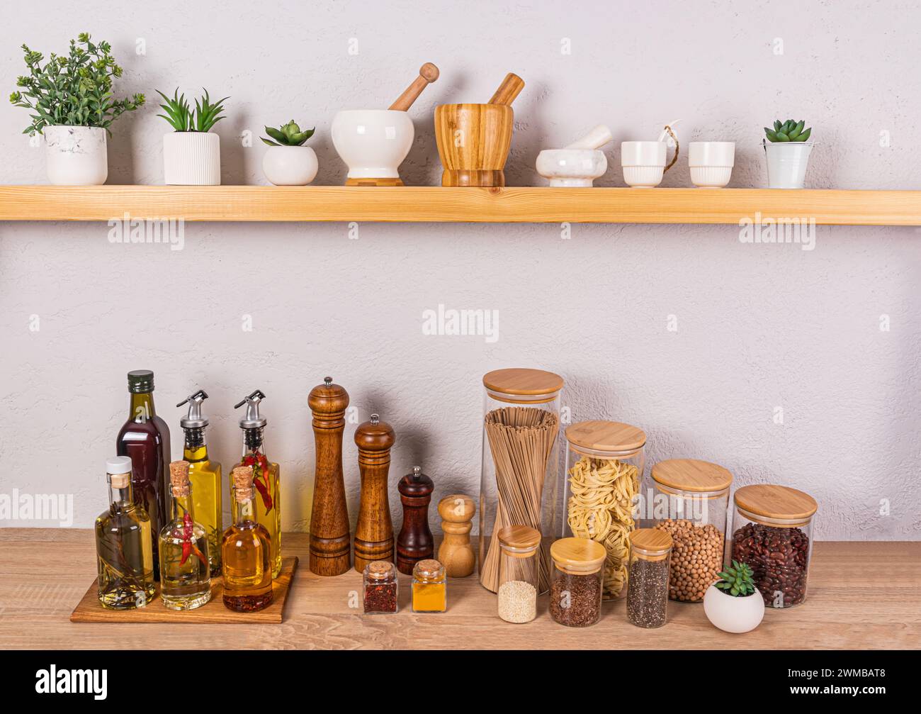 Fond de cuisine élégant avec un ensemble de bouteilles avec diverses huiles de cuisson, des pots en verre avec des épices. Vue de face d'une étagère en bois ouverte. Banque D'Images