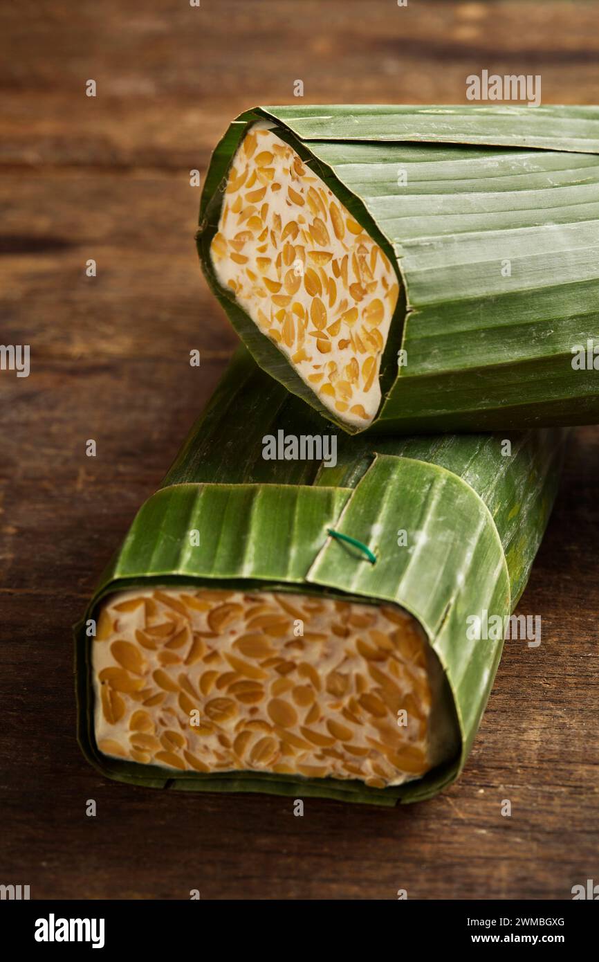 Tempeh cru enveloppé dans des feuilles de banane. Le tempeh est un aliment typiquement indonésien à base de soja fermenté et de plusieurs autres ingrédients Banque D'Images