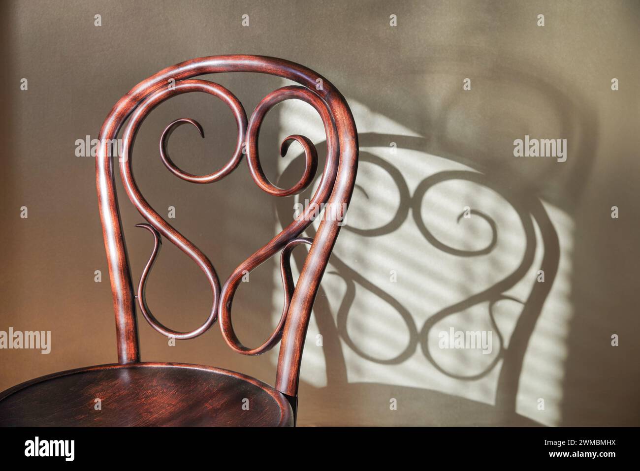 Chaise en bois rond antique magnifiquement travaillée et ornée dans le style de Thonet, créant une ombre complexe dans la lumière de l'après-midi. Banque D'Images