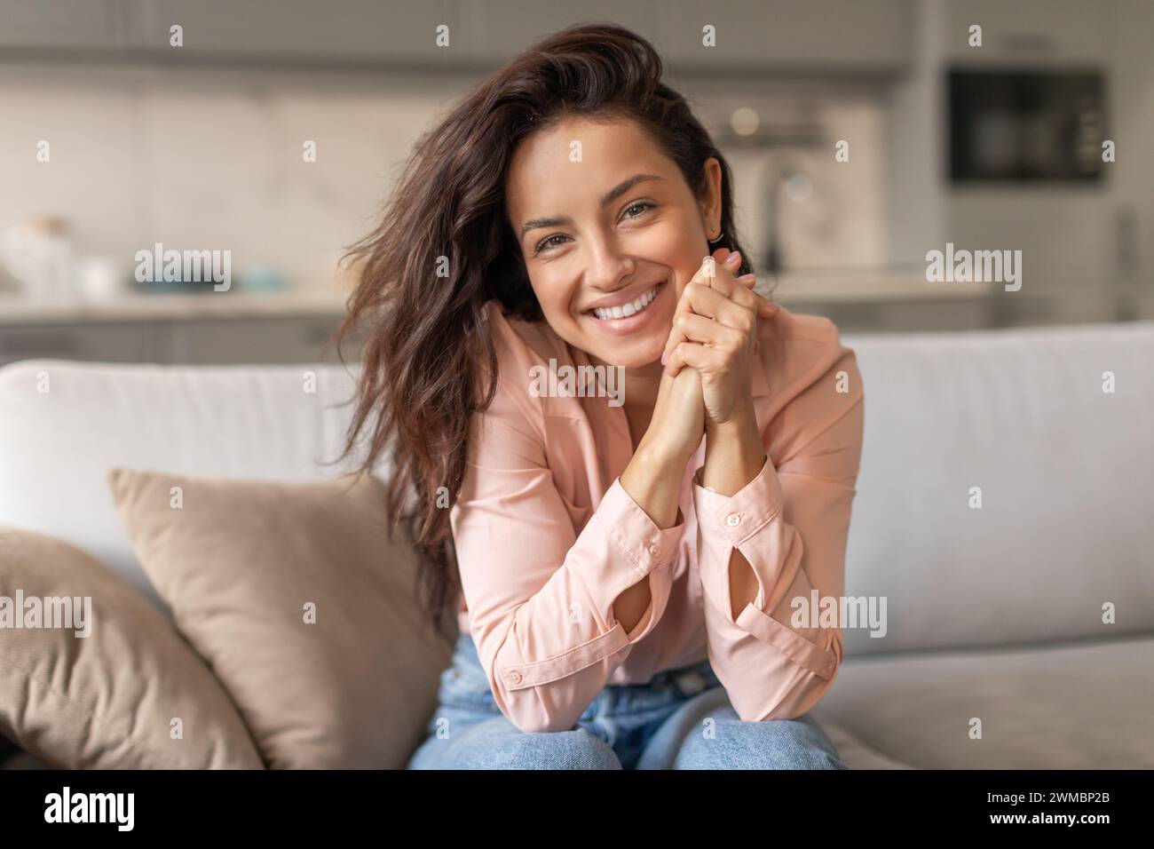 Femme avec un sourire lumineux reposant sur un canapé à la maison Banque D'Images