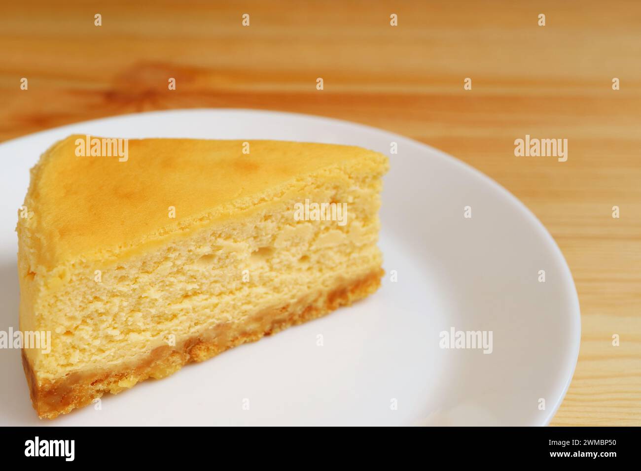 Tranche d'appétissant cheesecake cuit au four sur une assiette blanche Banque D'Images