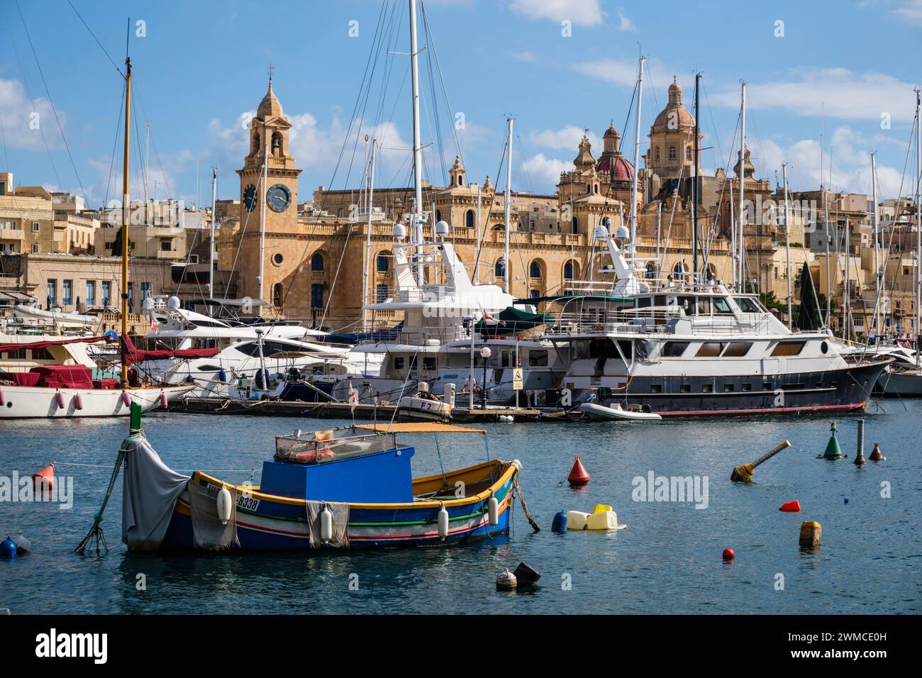 Un luzzu traditionnel contraste avec les yachts de luxe à Vittoriosa Yacht Marina - une vue sur le port depuis Senglea, la Valette, Malte Banque D'Images