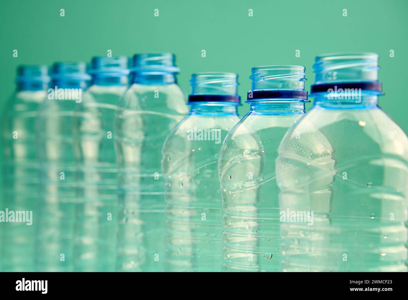 Gros plan de bouteilles en plastique transparentes ouvertes de différentes formes et tailles disposées en ligne sur fond vert Banque D'Images