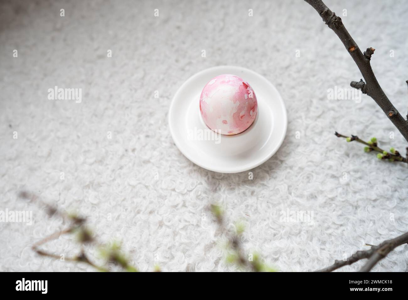 Vue aérienne d'un œuf de Pâques peint rose dans un coquetier sur une table à côté d'un ranch de printemps Banque D'Images