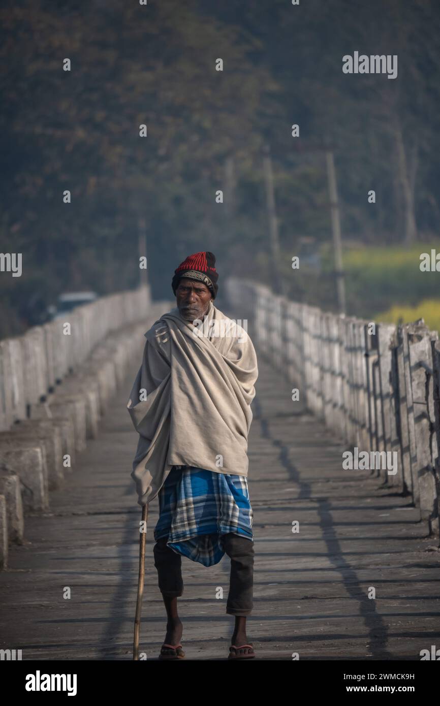 Un homme marche à travers le pont en hiver matin tenant un bâton de bambou Banque D'Images