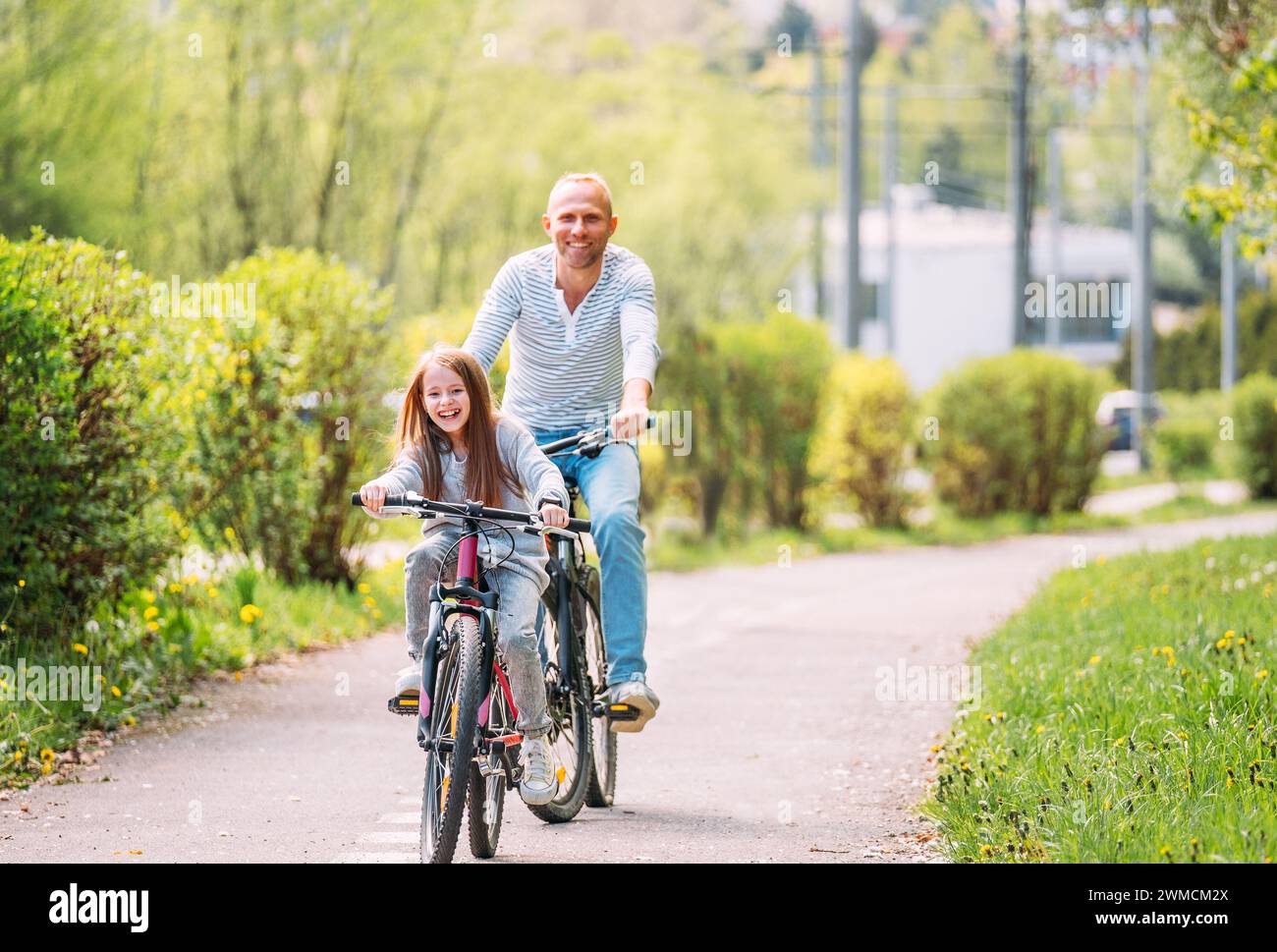 Portraits souriant père avec fille pendant l'été randonnée à vélo en plein air. Ils apprécient la convivialité dans le parc de la ville d'été. Bonne parentalité et chi Banque D'Images