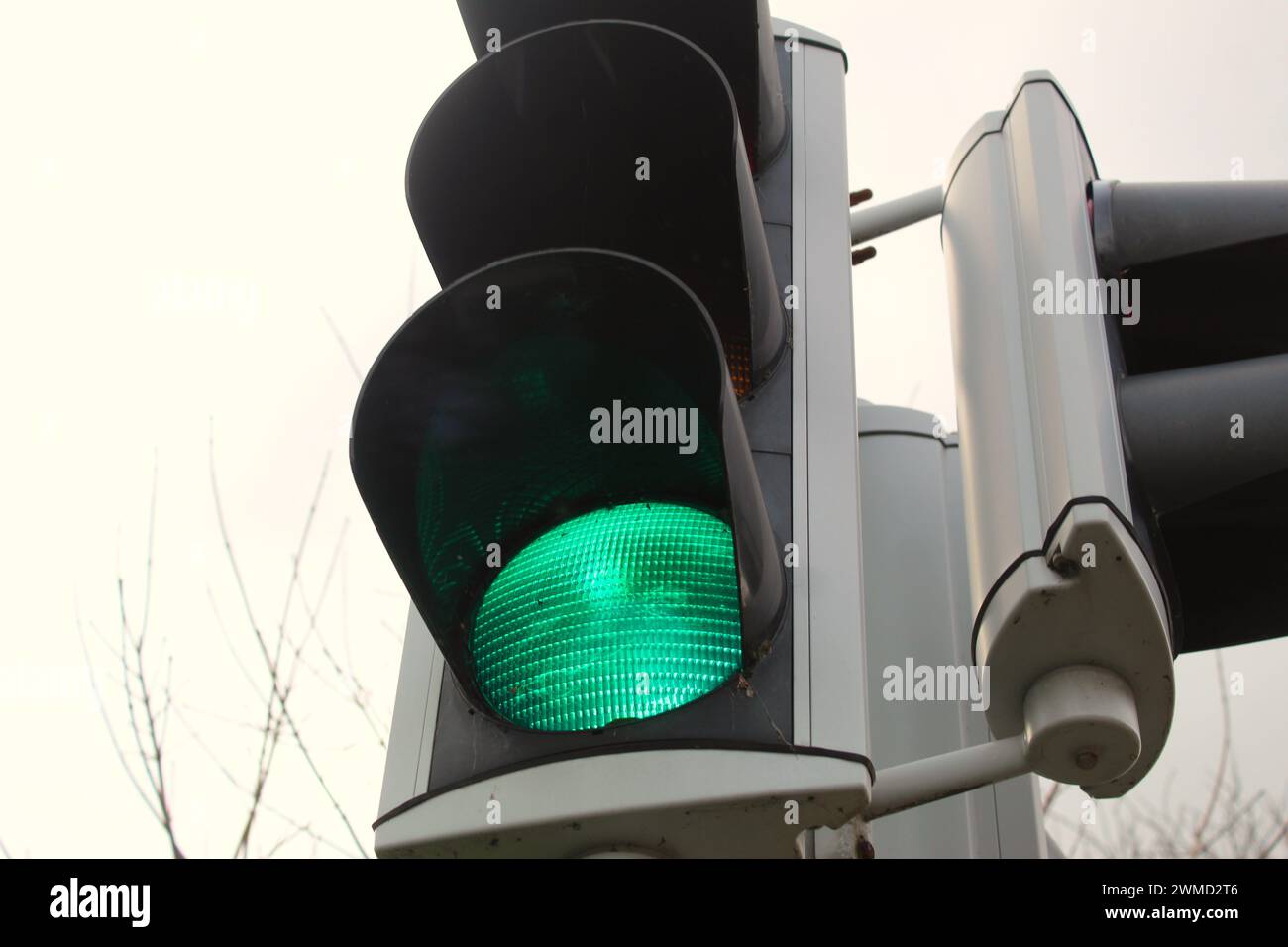 Une photo d'un feu de circulation vert contre un ciel blanc. Banque D'Images