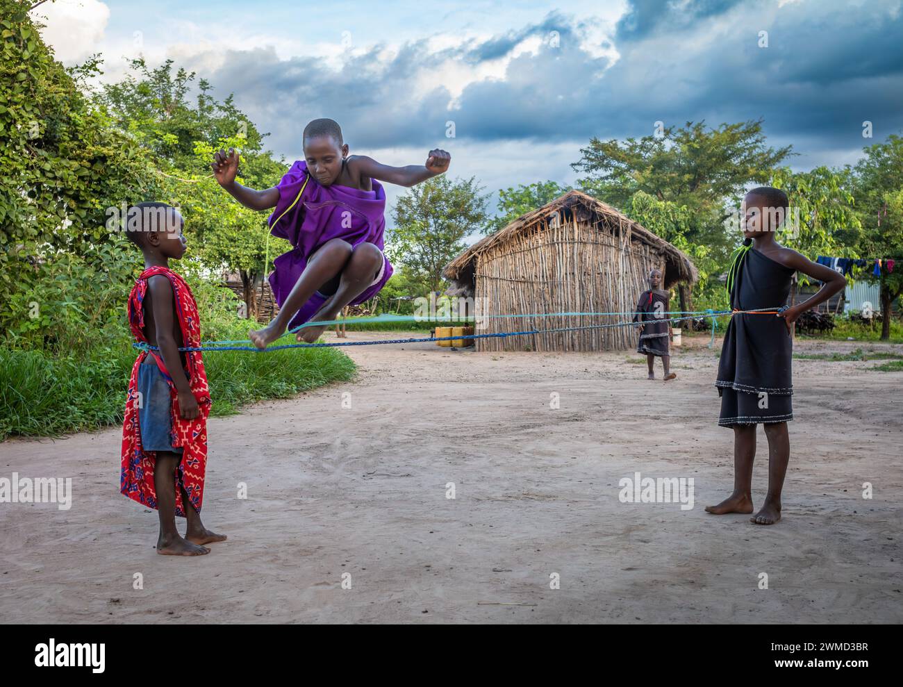 De jeunes enfants Massaï jouent à un jeu de saut et de saut dans leur village traditionnel de Mikumi, en Tanzanie. Banque D'Images
