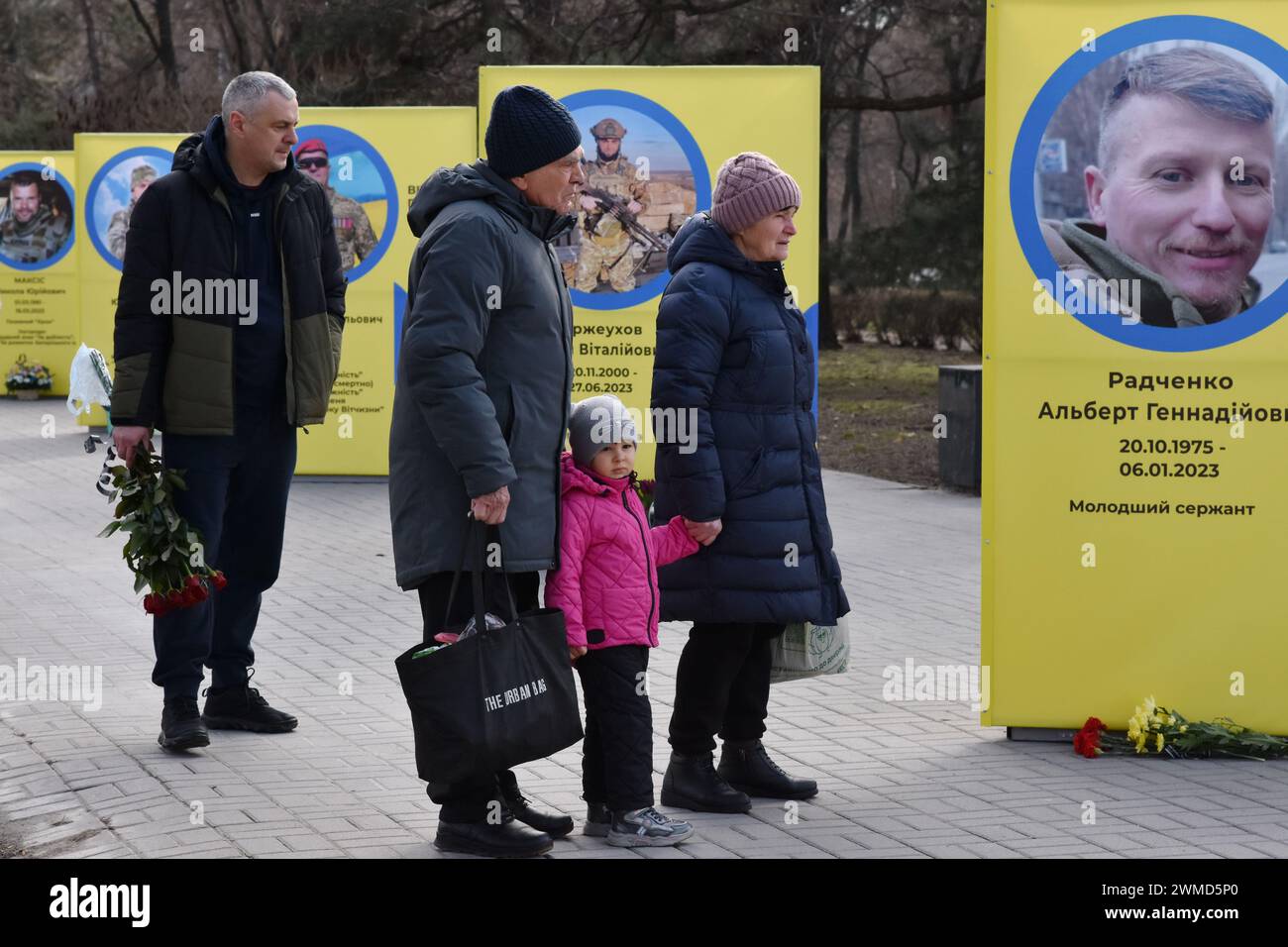 Parents et amis sont vus à côté des stands de portraits de soldats ukrainiens tombés au combat dans le centre de Zaporizhzhia. Le président ukrainien Volodymyr Zelensky a marqué le deuxième anniversaire de l'invasion russe en déclarant que son pays "réussira". L'Ukraine a défié les prédictions de combattre la Russie, mais il y a des signes que la guerre tourne en faveur de la Russie. Le gouvernement ukrainien a cessé de partager le nombre de ses militaires morts il y a longtemps. Mais le nombre toujours croissant de tombes fraîches, des deux côtés des lignes de front, dresse un tableau douloureusement clair. Banque D'Images