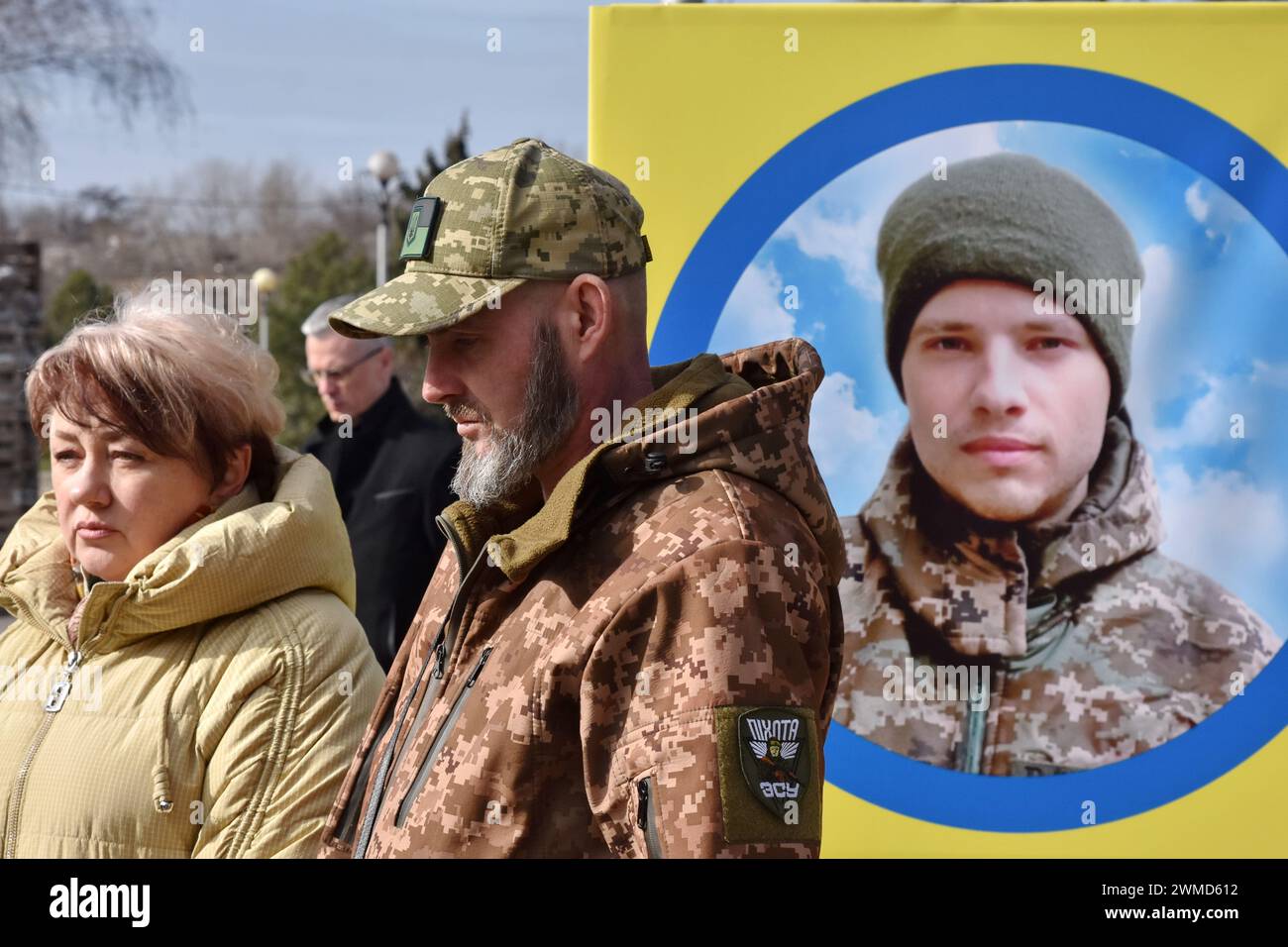 Parents et amis sont vus par le stand de portrait du soldat ukrainien tombé dans le centre de Zaporizhzhia. Le président ukrainien Volodymyr Zelensky a marqué le deuxième anniversaire de l'invasion russe en déclarant que son pays "réussira". L'Ukraine a défié les prédictions de combattre la Russie, mais il y a des signes que la guerre tourne en faveur de la Russie. Le gouvernement ukrainien a cessé de partager le nombre de ses militaires morts il y a longtemps. Mais le nombre toujours croissant de tombes fraîches, des deux côtés des lignes de front, dresse un tableau douloureusement clair. Banque D'Images