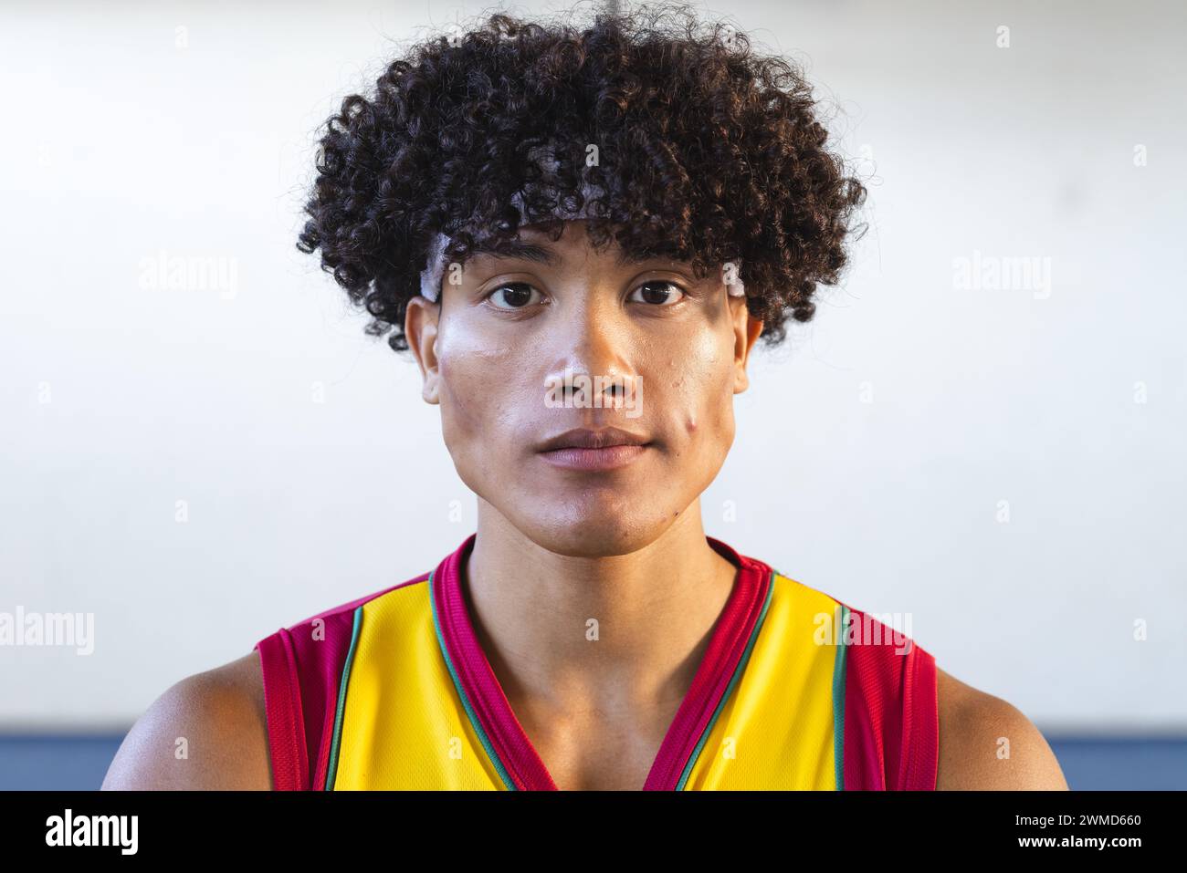 Jeune homme biracial dans un maillot de basket pose avec confiance Banque D'Images
