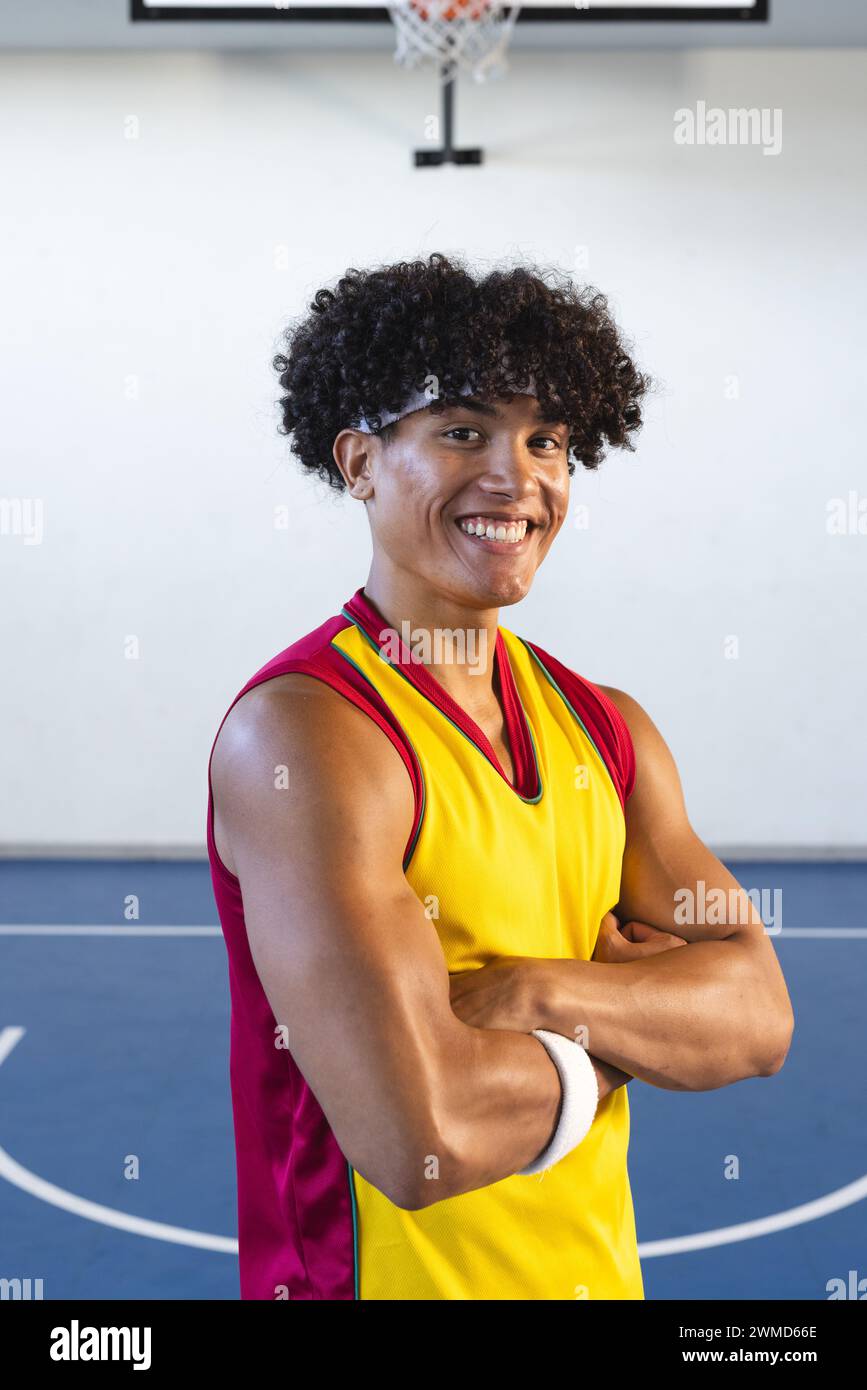 Jeune homme biracial pose avec confiance sur un terrain de basket-ball Banque D'Images