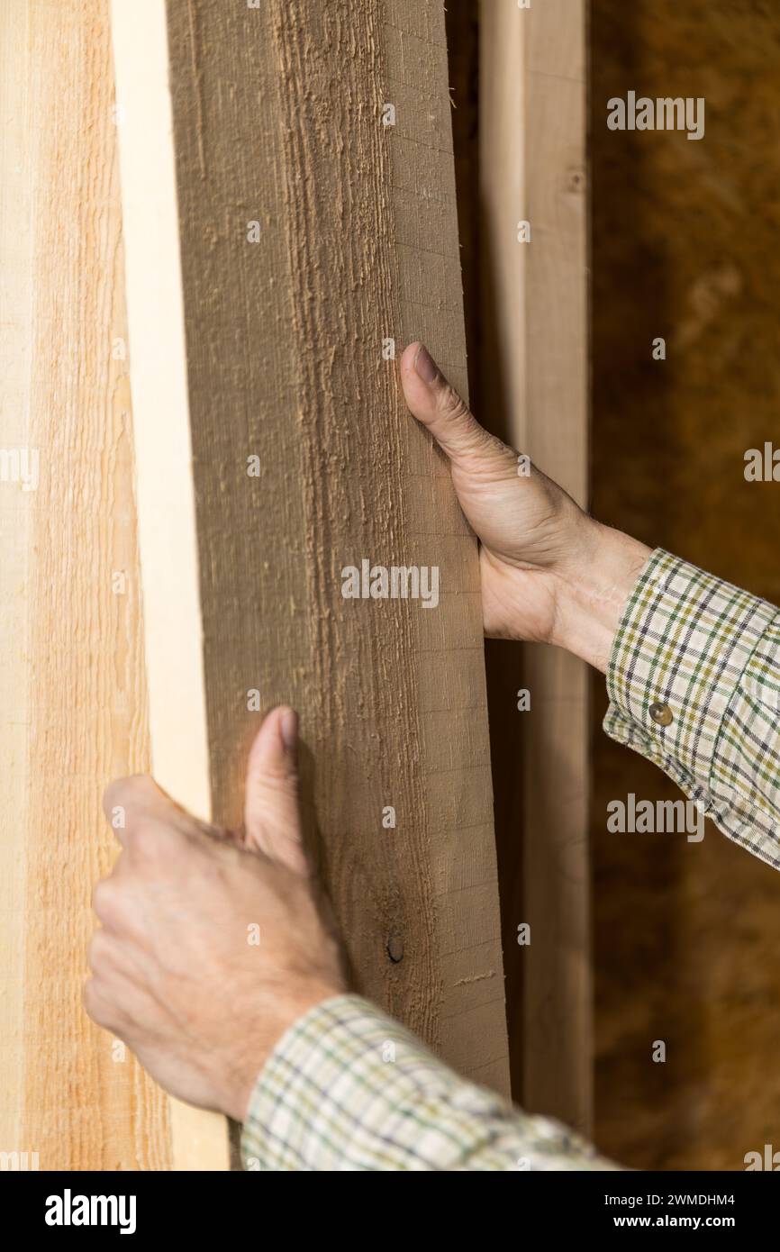 Photo verticale un menuisier qualifié inspecte la qualité du bois dans un atelier, ses mains évaluant la texture et le grain pour l'artisanat.Copier l'espace. Busi Banque D'Images