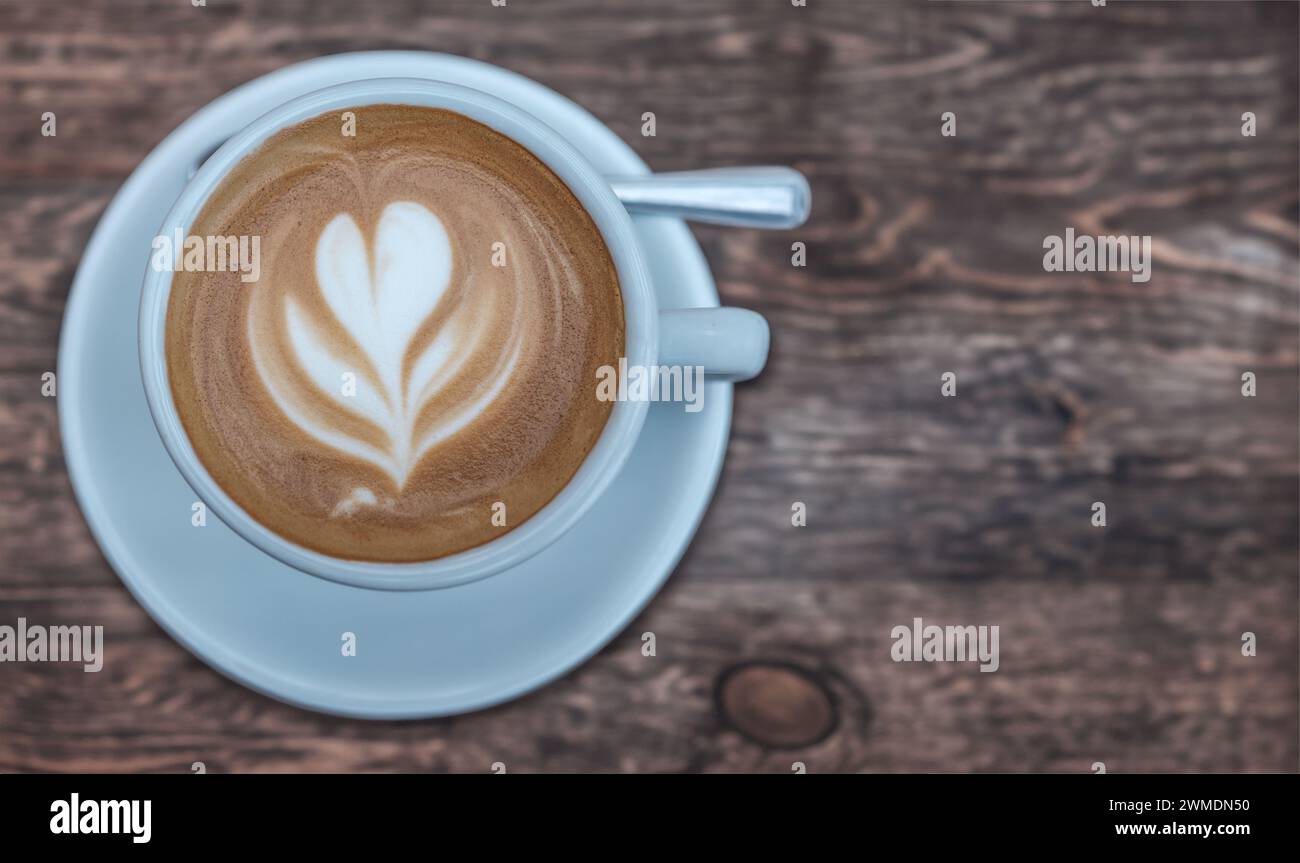 Une tasse de café, avec Latte Art dans le lait mousseux, sur Une table de café rustique avec espace de copie Banque D'Images