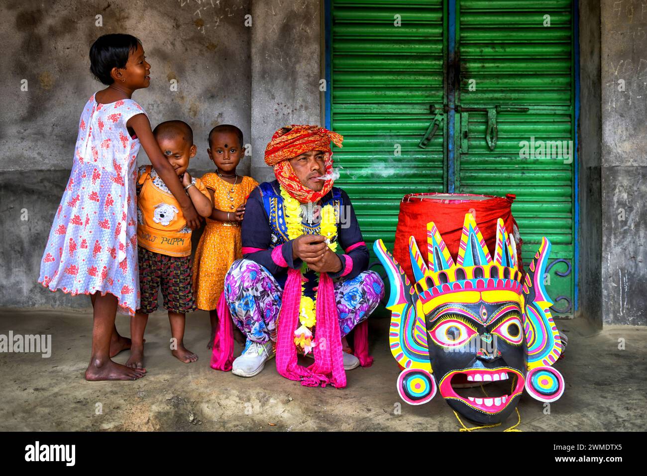Un danseur masqué de danse de Gomira vu avec ses enfants. Gomira est une forme de danse masquée. Le mot «Gomira» est dérivé de la forme familière du mot «Gram-Chandi» ou la divinité féminine qui est la force protectrice du village. L'origine exacte de la forme de danse n'est pas traçable et la connaissance a été perdue au fil du temps. La danse Gomira est une forme de danse rurale principalement pratiquée dans le district de Dinajpur au Bengale occidental. Les danses Gomira sont organisées pour apaiser la divinité pour inaugurer les «bonnes forces» et chasser les «mauvaises forces». Il est généralement organisé de mi-février à mi-juillet. Th Banque D'Images