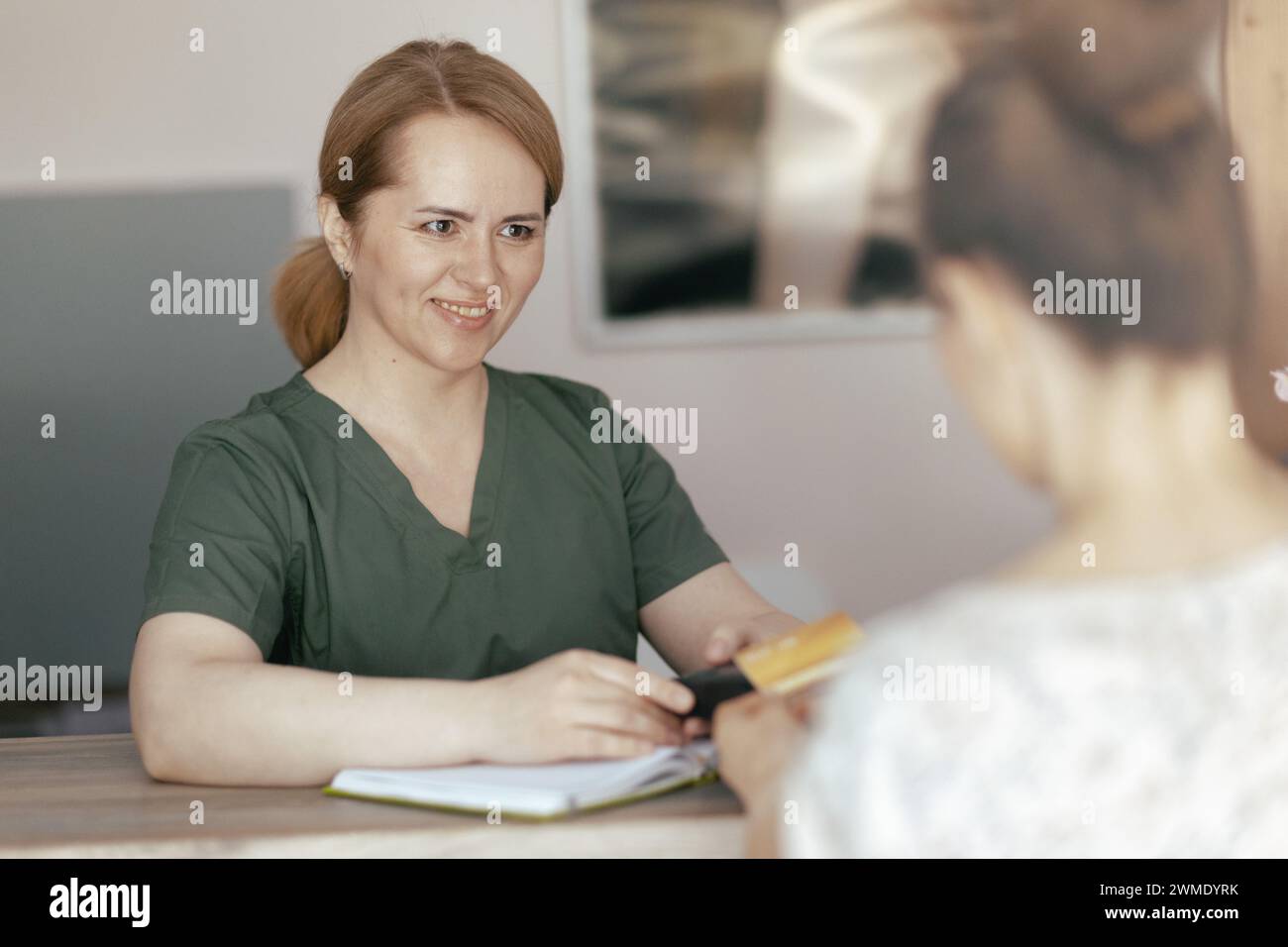 Le temps des soins de santé. souriant femme massothérapeute médicale dans l'armoire de massage avec le client acceptant les paiements par carte de crédit via le terminal à la réception. Banque D'Images