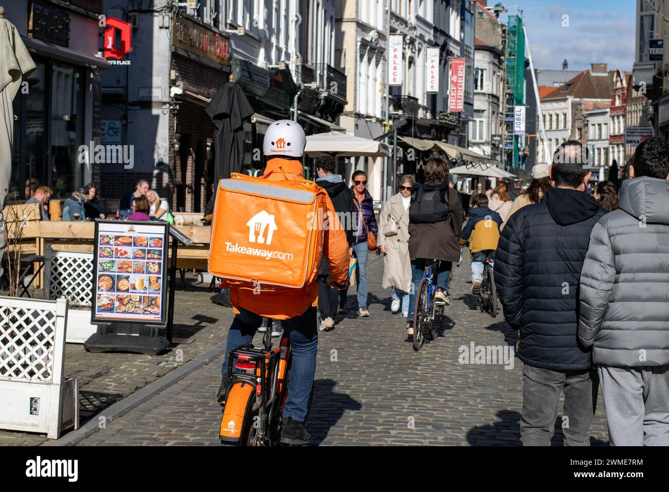 Gand, Belgique - janvier 31 2024 : livreur de nourriture glissant dans l'agitation d'une rue animée, apportant des repas à la porte. À emporter Banque D'Images