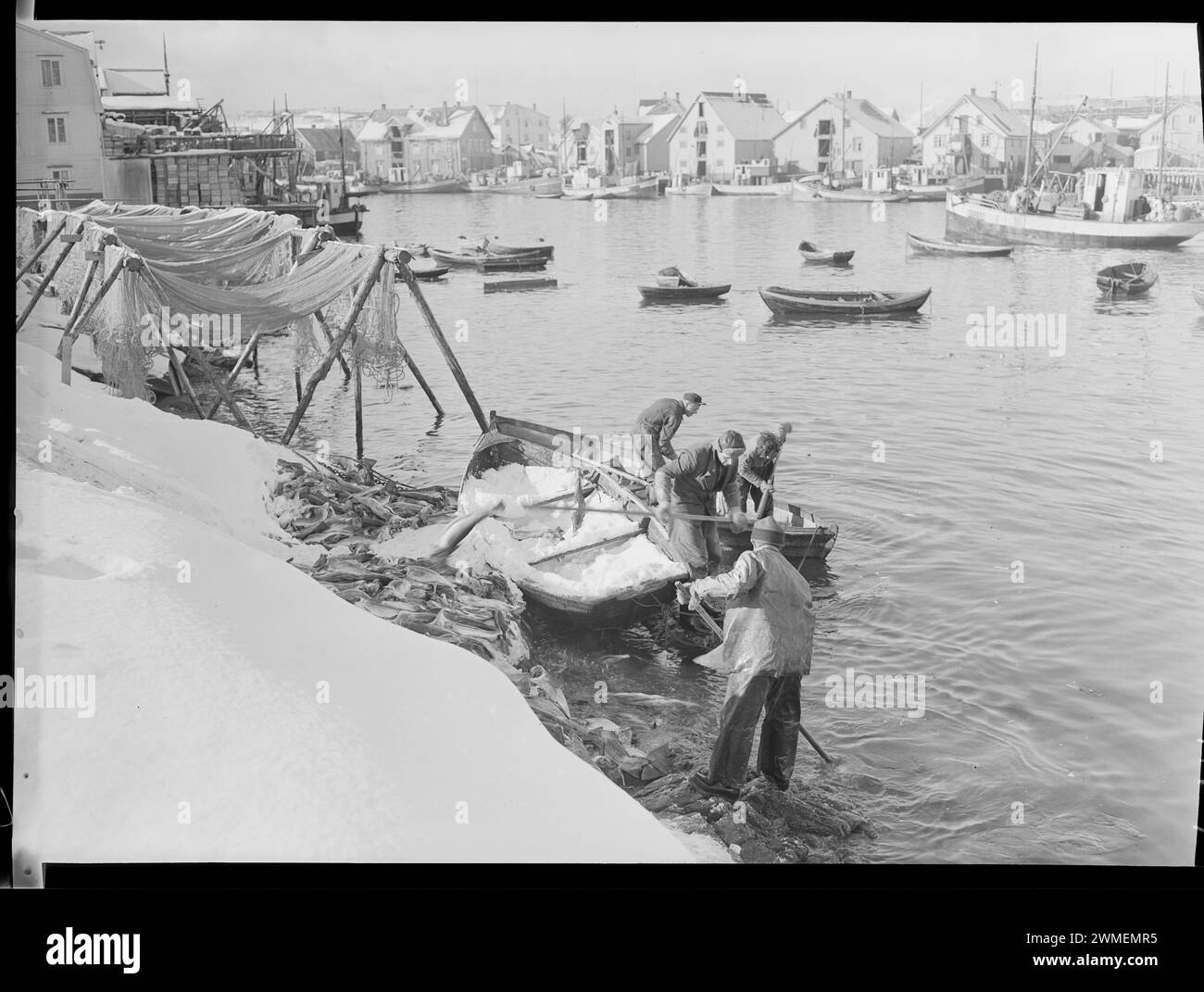 Photographie vintage d'un village de pêcheurs norvégien en hiver, avec un pêcheur en dingy, roibu à l'arrière, vers les années 1920 Banque D'Images