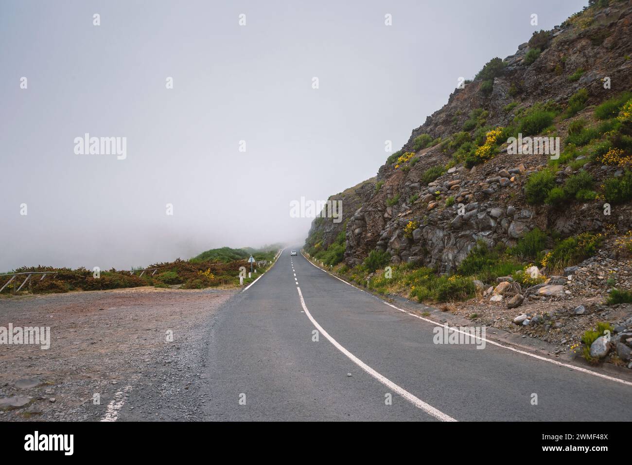 Route de montagne brumeuse avec voiture lointaine sur l'île de Madère, Portugal Banque D'Images