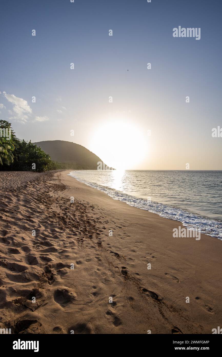 Vue sur une plage, la côte et la mer au coucher du soleil. Au premier plan la plage de sable vide de Grande Anse, basse Terre, Guadeloupe, Antilles françaises Banque D'Images