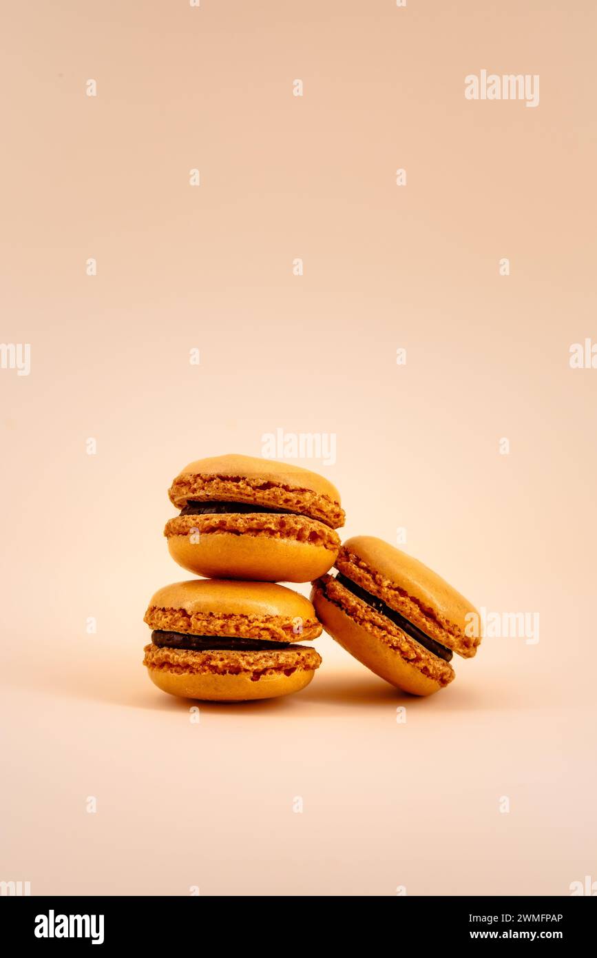 Macarons français oranges sur un fond de couleur pastel Uni Banque D'Images