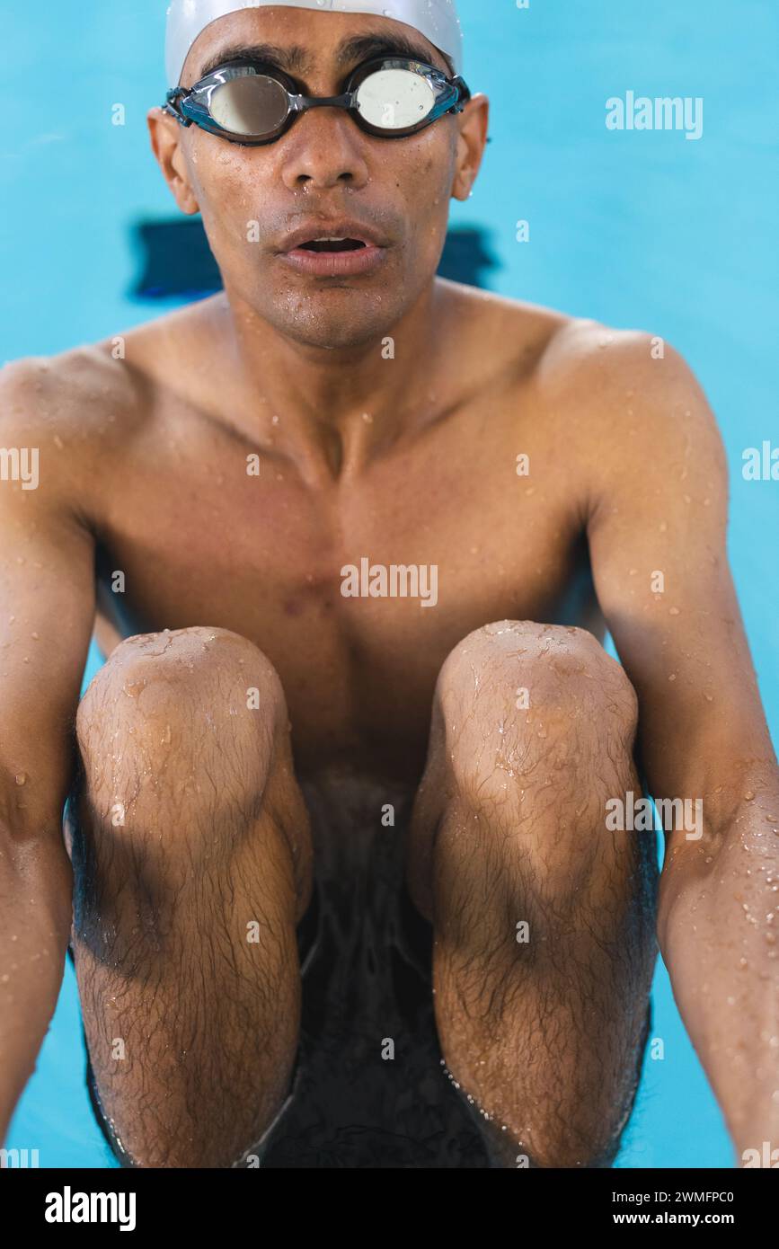 Jeune nageur athlète masculin biracial émerge d'une piscine, vêtu de lunettes Banque D'Images