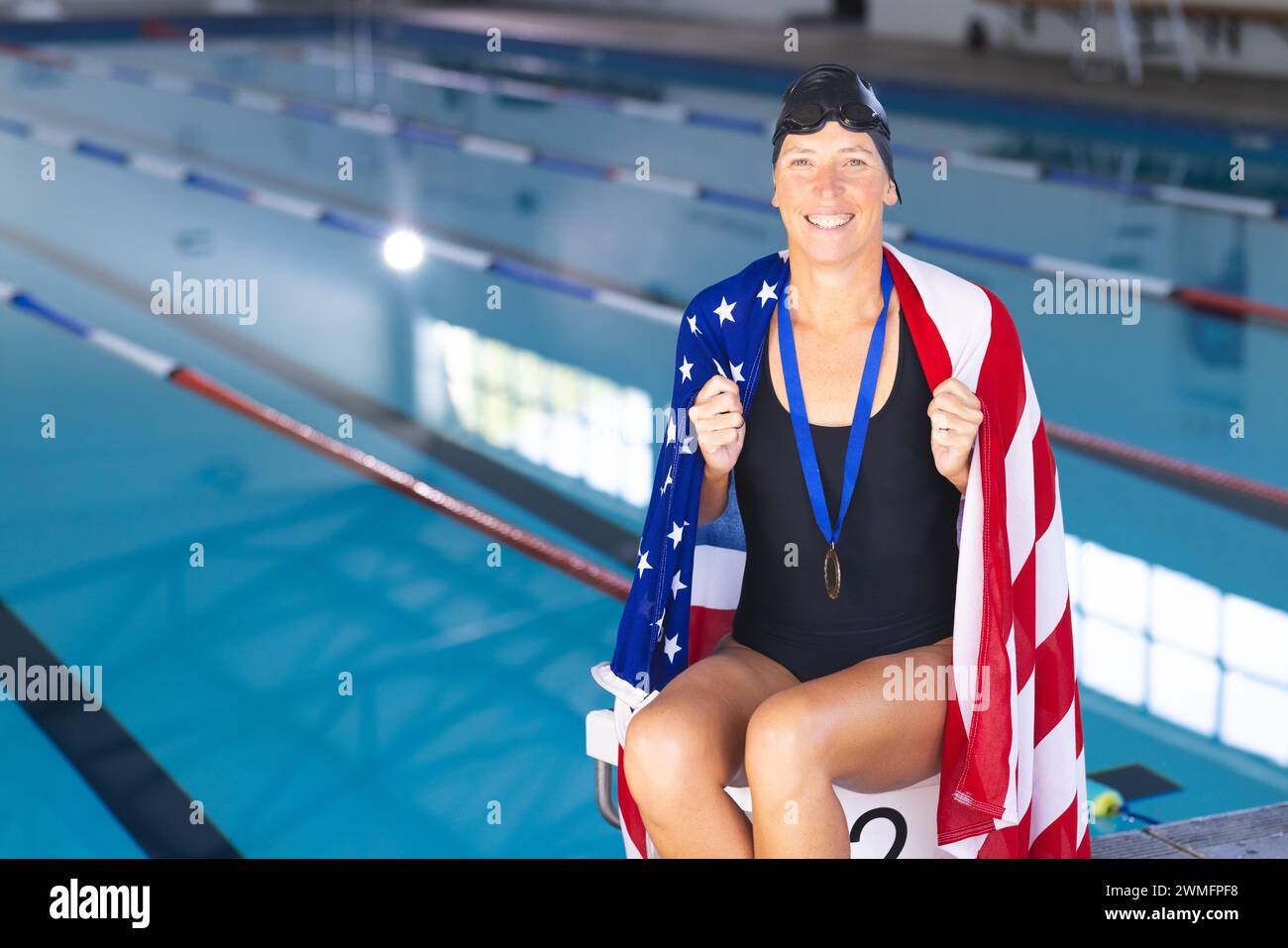 Fier athlète enveloppé dans le drapeau américain dans une piscine avec une médaille Banque D'Images