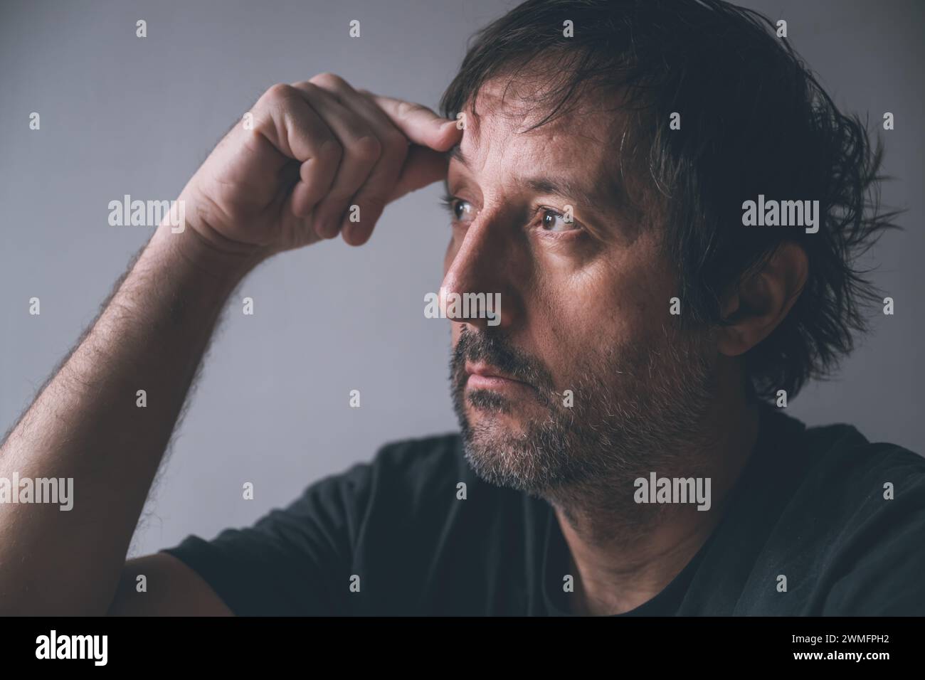 Concept de paralysie de surpensée et d'analyse, portrait d'un homme pensif unkempt regardant vers la lumière qui vient de la fenêtre, focu sélectif Banque D'Images