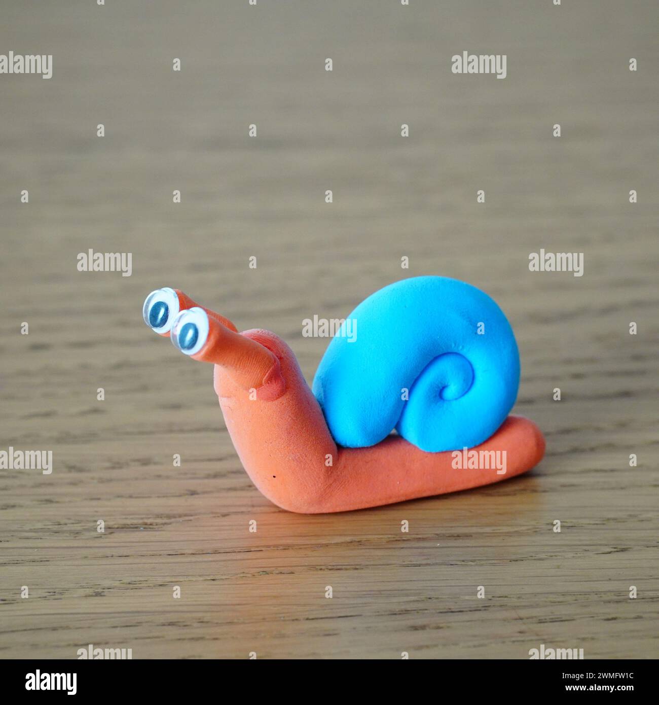 Un escargot jouet avec des yeux repose sur une surface de table en bois Banque D'Images