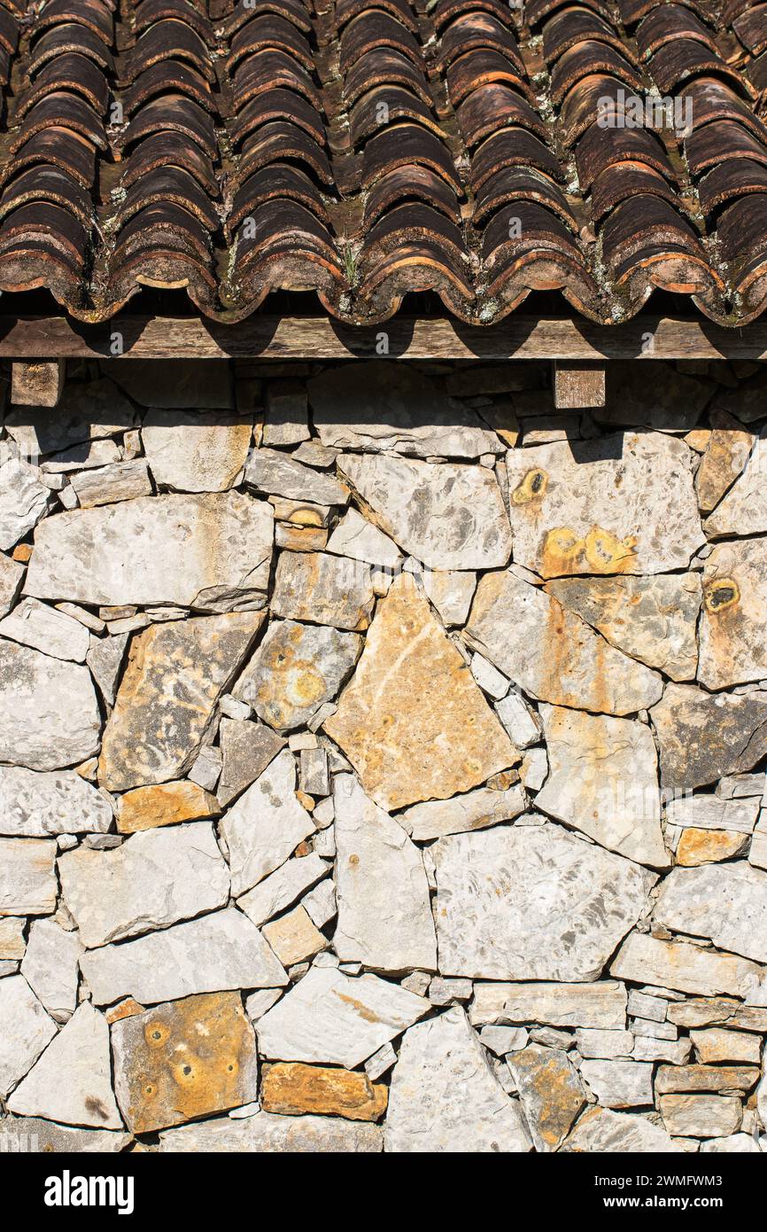 Un mur de pierre rustique et un toit avec des carreaux de céramique Banque D'Images