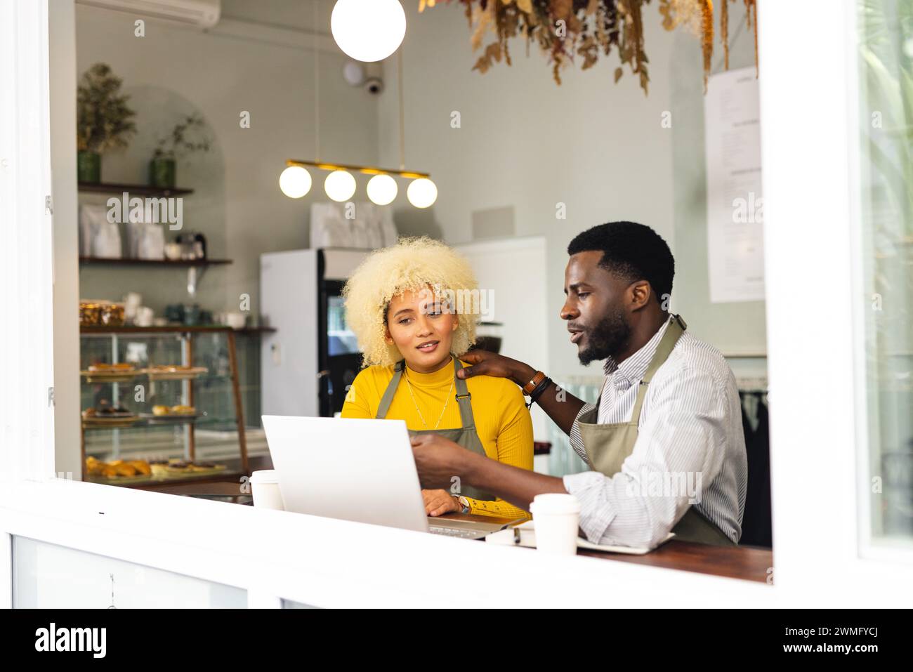Homme afro-américain assiste une femme biraciale dans un café, avec un espace de copie Banque D'Images