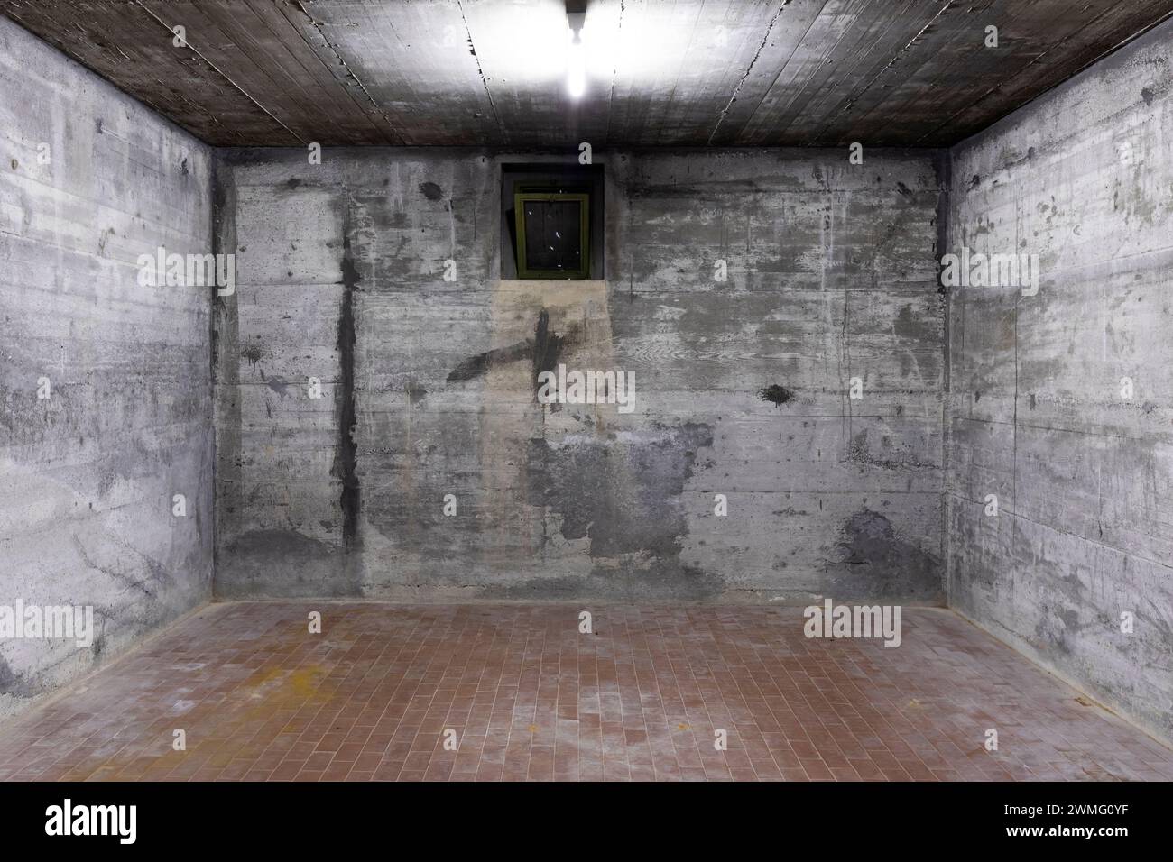 Vue de face du mur en béton armé avec une petite fenêtre pour l'air. Scène éclairée par une lampe au néon blanc. Personne à l'intérieur Banque D'Images