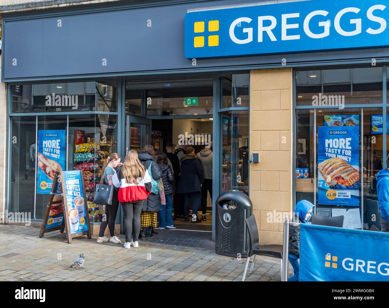 File d'attente à l'heure du déjeuner pour des rafraîchissements à Greggs, High Street, Lincoln City, Lincolnshire, Angleterre, ROYAUME-UNI Banque D'Images