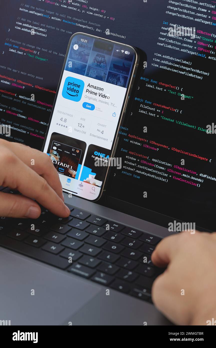 New York, États-Unis - 23 février 2024 : Code pour la nouvelle application vidéo Amazon prime dans l'écran d'ordinateur portable avec les mains sur le clavier Banque D'Images