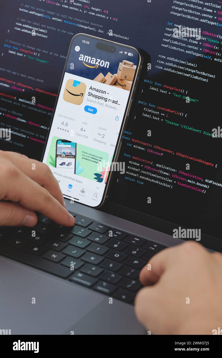 New York, États-Unis - 23 février 2024 : Code pour la nouvelle application Amazon shopping dans l'écran d'ordinateur portable avec les mains sur le clavier Banque D'Images