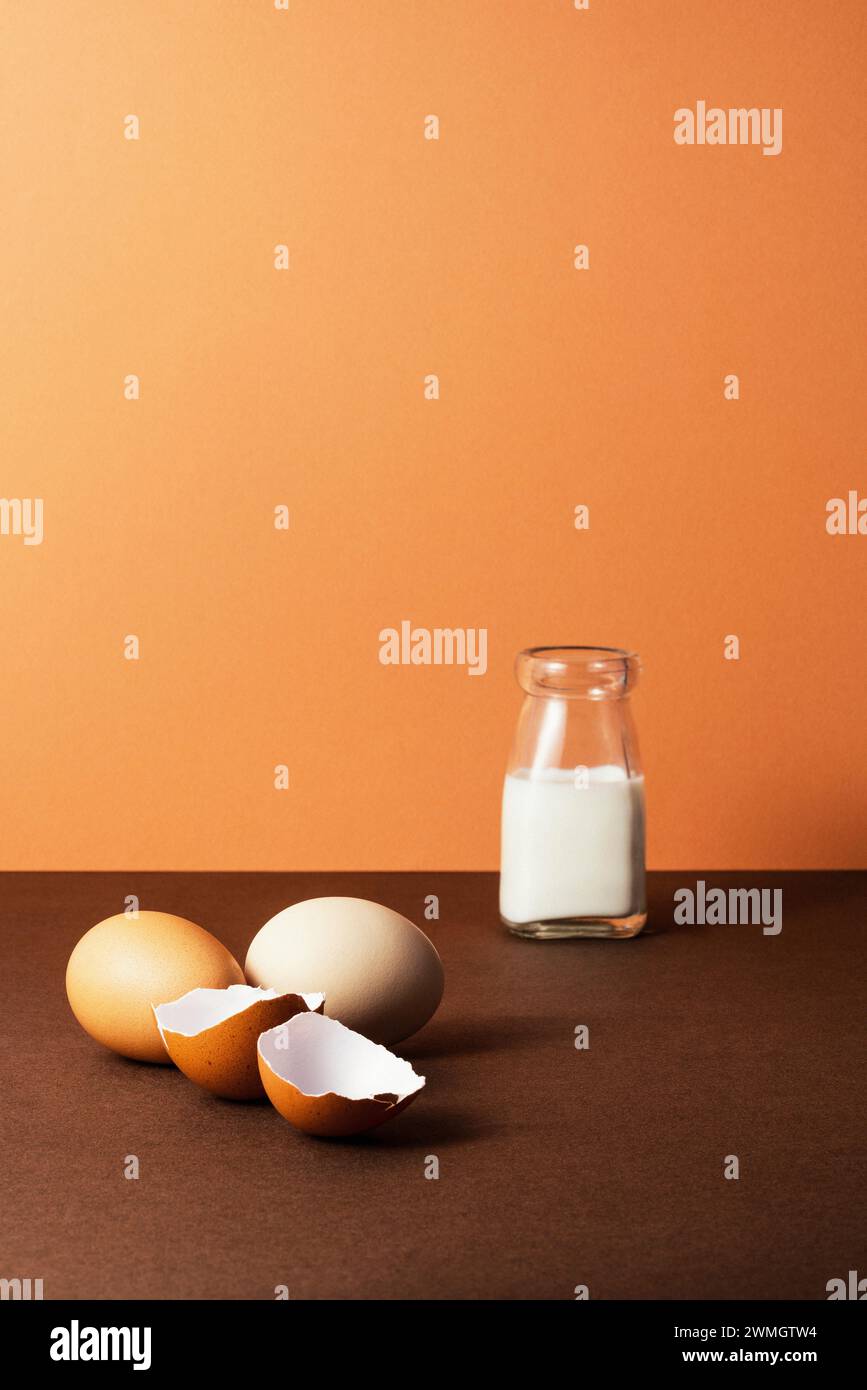 Trois œufs avec du lait dans une bouteille en verre sur fond brun, studio tourné avec des ombres nettes et un contraste élevé Banque D'Images
