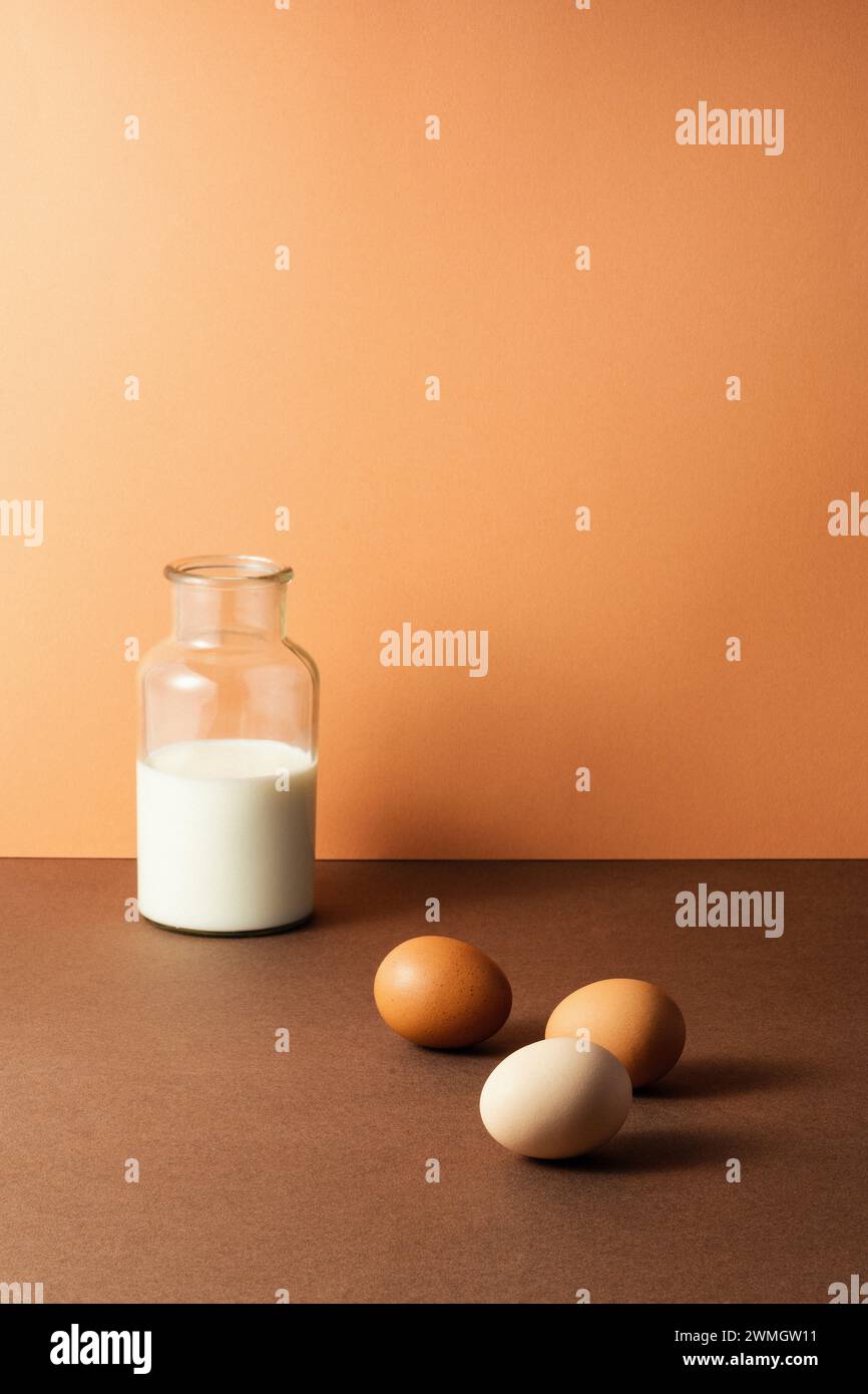 Trois œufs avec du lait dans une bouteille en verre sur fond brun, studio tourné avec des ombres nettes et un contraste élevé Banque D'Images
