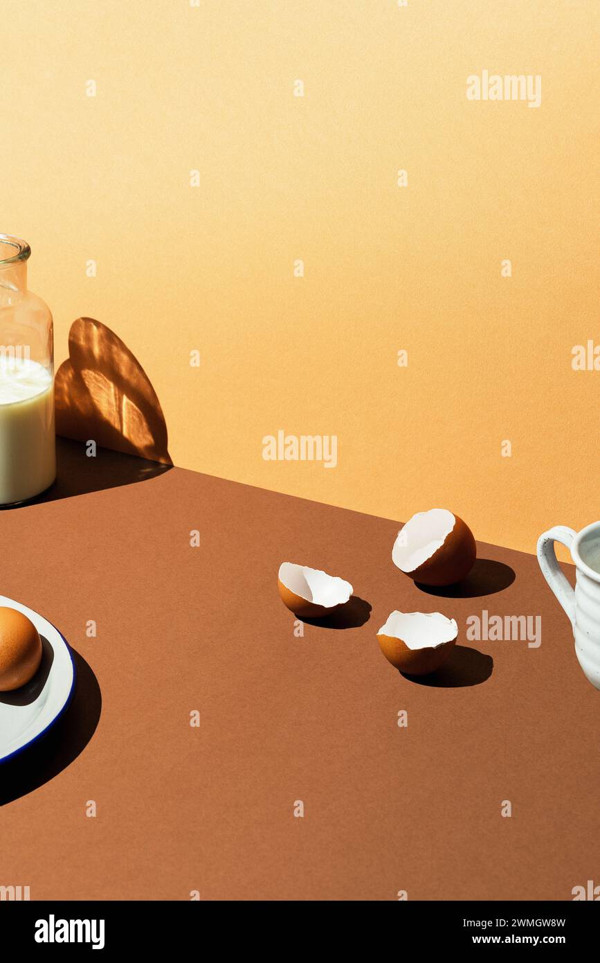Coquilles d'oeufs avec du lait dans une bouteille en verre sur fond brun. Effet de lumière du soleil, prise de vue à angle élevé. Banque D'Images