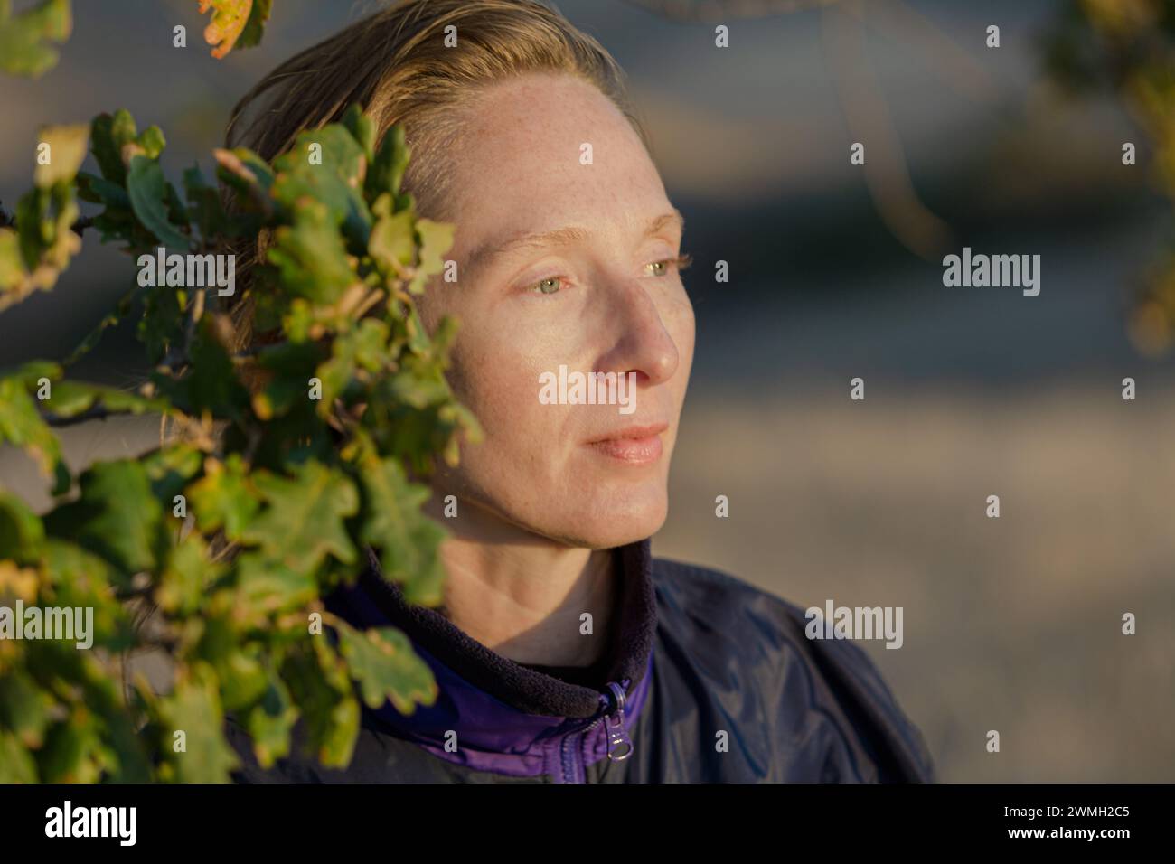 Portrait de profil dans les rayons d'un coucher de soleil. Femme caucasienne adulte avec un sourire réservé. Banque D'Images