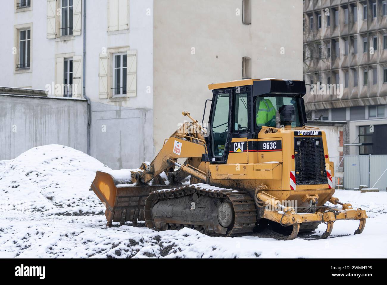 Nancy, France - Chargeuse sur chenilles jaune CAT 963C pour travaux de terrassement sur chantier sous la neige. Banque D'Images