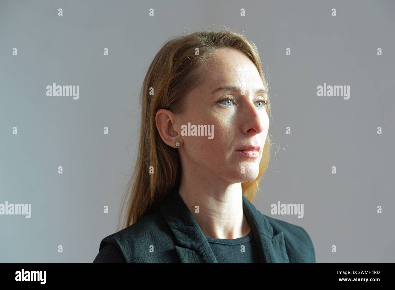 Portrait de profil d'une jeune femme attirante adulte dans un costume noir sur un fond blanc avec une expression sévère sur son visage. Banque D'Images