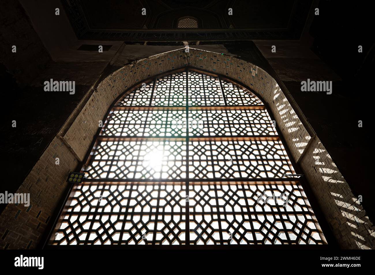Fenêtre de style oriental avec bar et soleil qui brille à travers elle. la calandre sur la vitre. Style islamique traditionnel dans l'architecture et l'intérieur du Banque D'Images
