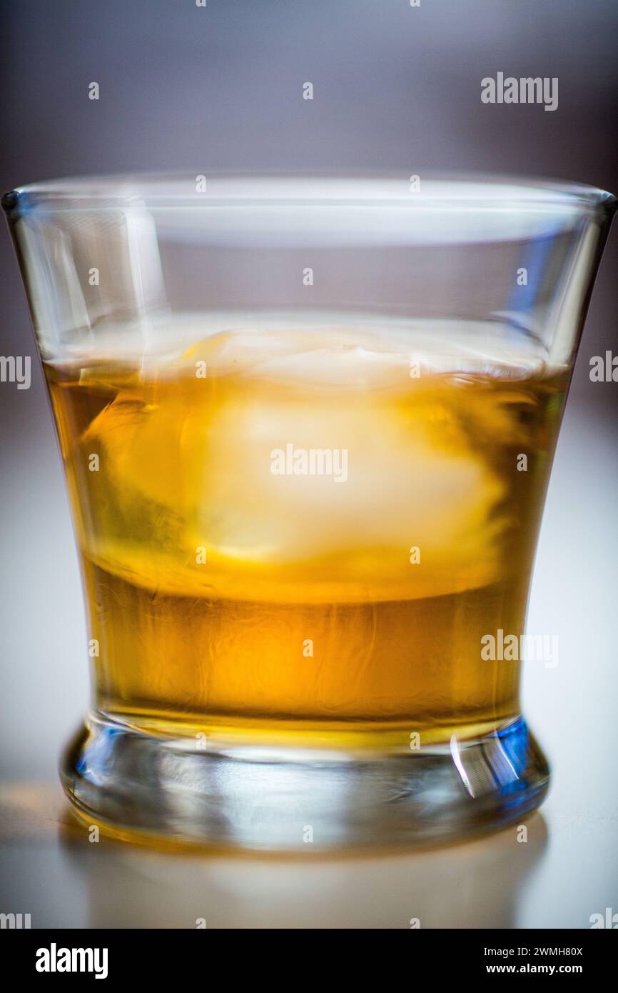 Un whisky pur single malt servi avec un grand glaçon dans un verre. Banque D'Images