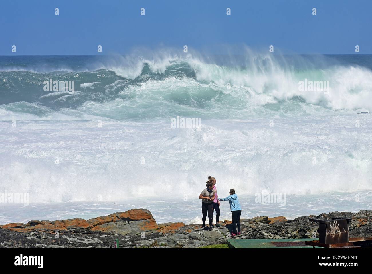 Trois filles regardant des vagues féroces se briser sur la rivière Storms au parc national de Tsitsikamma près de Knysna, Western Cape, Afrique du Sud Banque D'Images